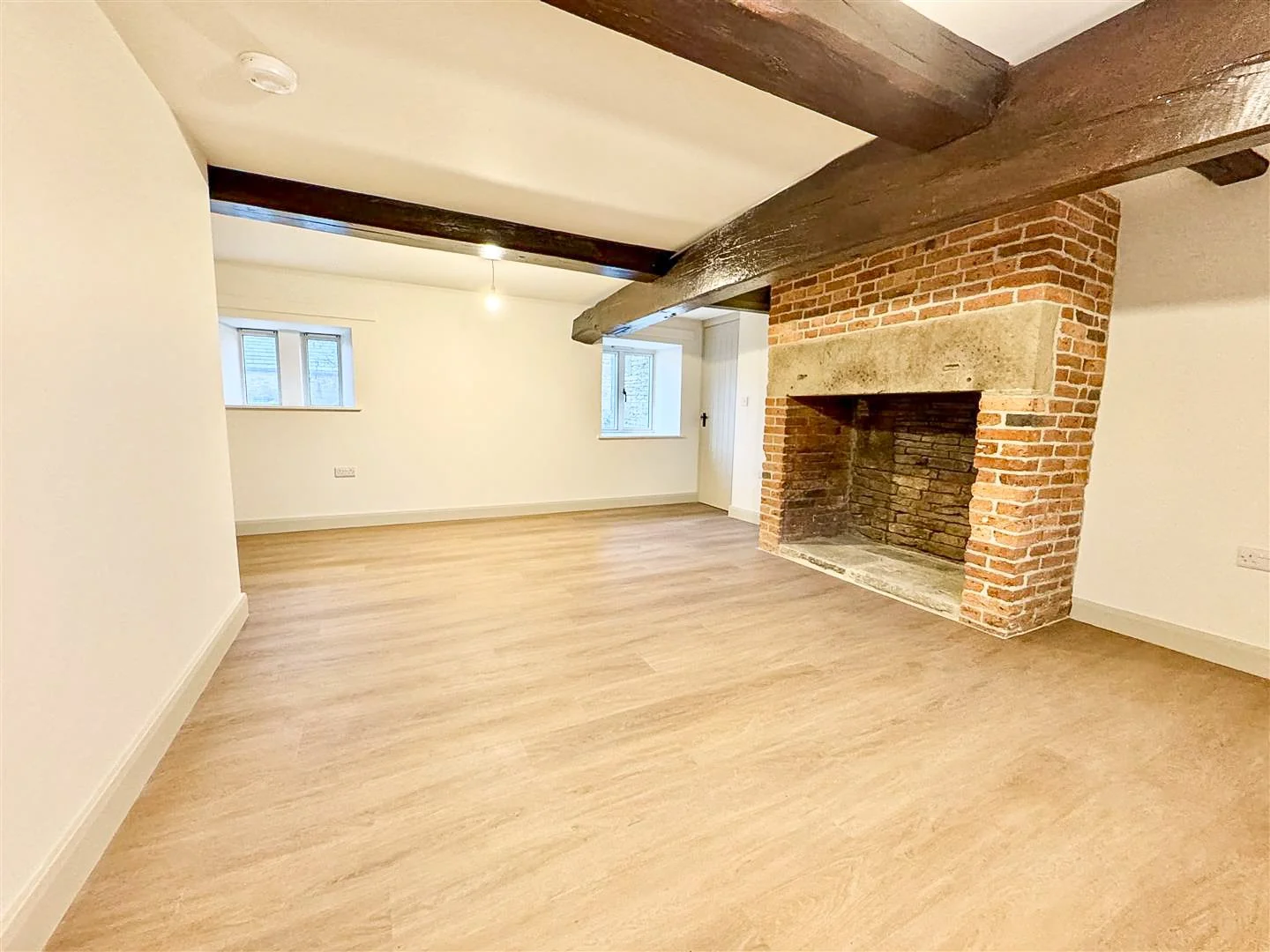 Completed living room renovation featuring exposed timber beams, restored fireplace and modern finishes.