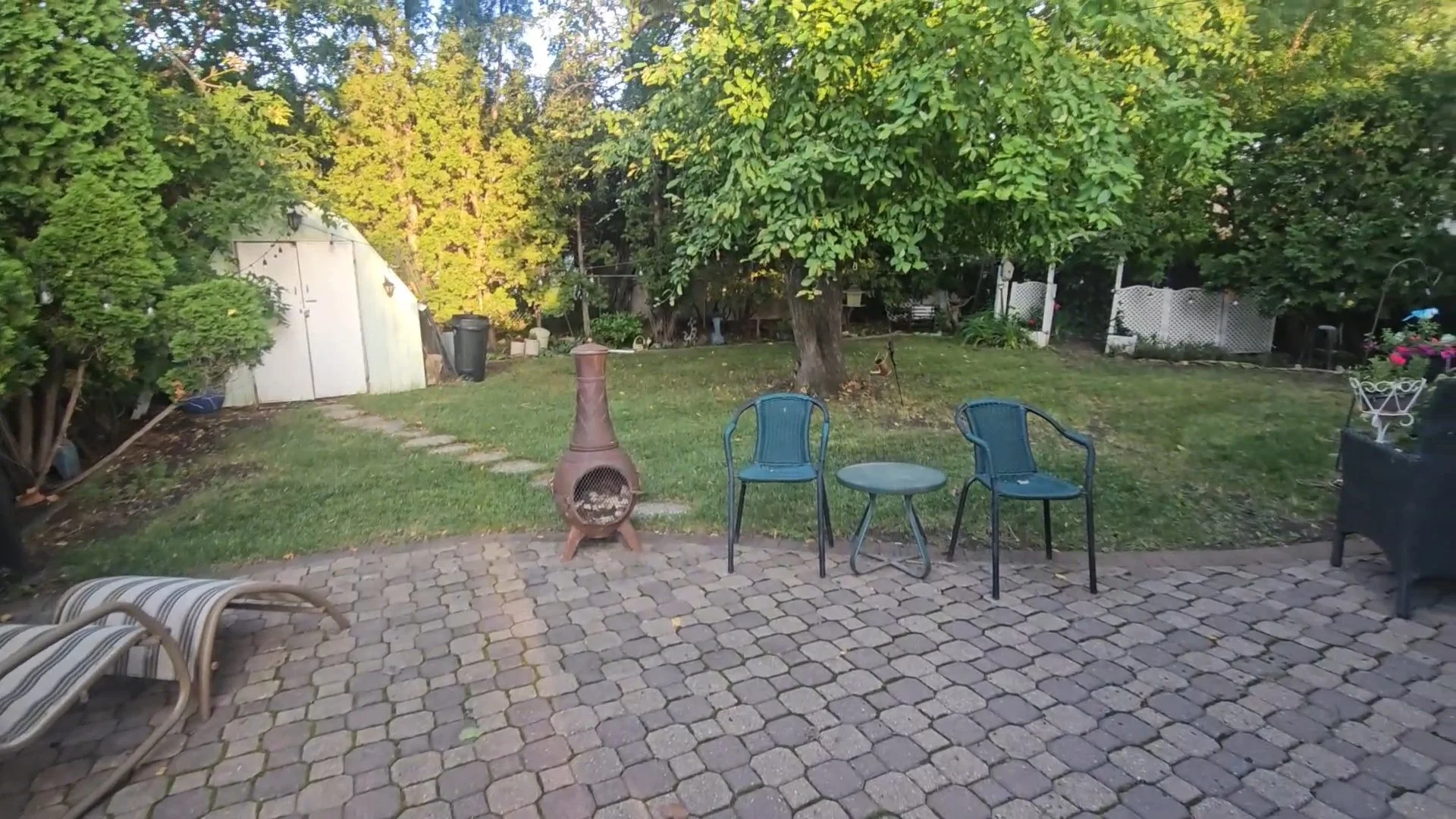 Norstead Fresh Start project: backyard lawn, mature trees and a cleared patio with seating.