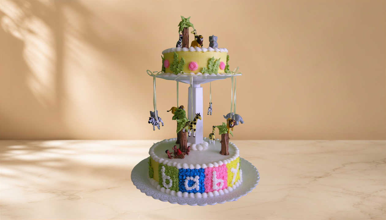 Colorful jungle-themed cake with animals and trees, decorated with the name "Baby" in multicolored letters.
