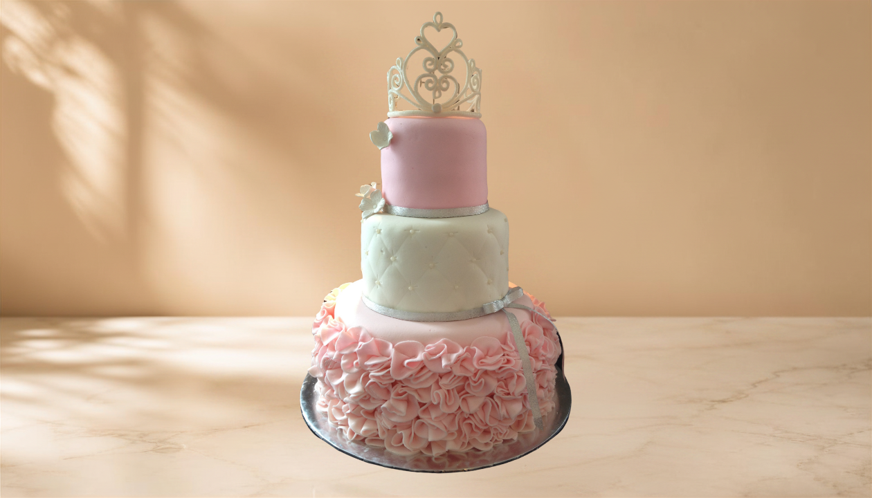 Decorative multi-tiered pink and white wedding cake with a tiara on top, placed on a silver tray, with a neutral background.