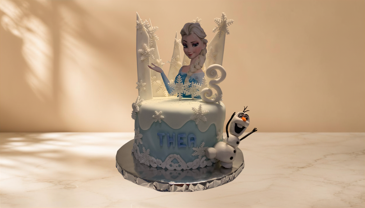 Frozen-themed birthday cake with Elsa and Olaf decorations, featuring snowflakes, a number 3, and the name 'Thea'.