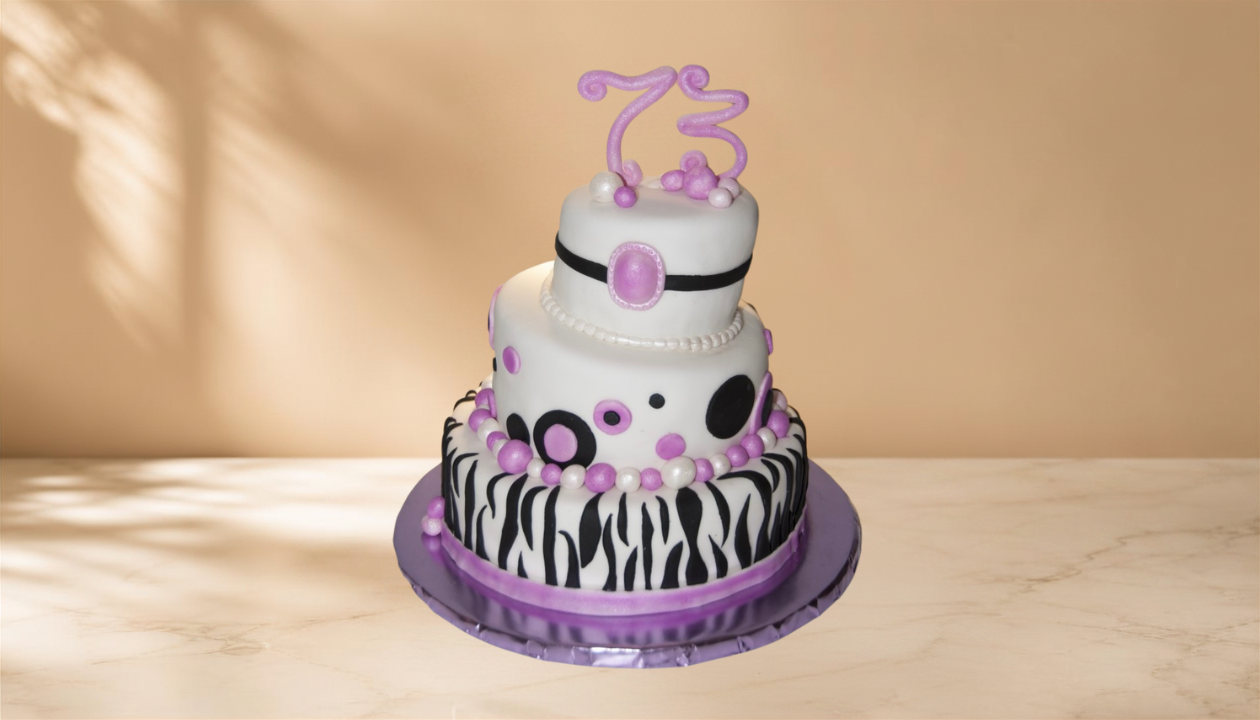 A three-tier birthday cake decorated in black, white, and purple, with animal print and abstract polka dot patterns, topped with a purple number 3 candle.
