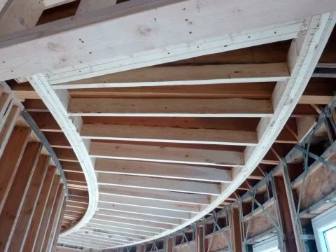 Interior view of a wooden ceiling under construction with exposed beams and framing in a building.