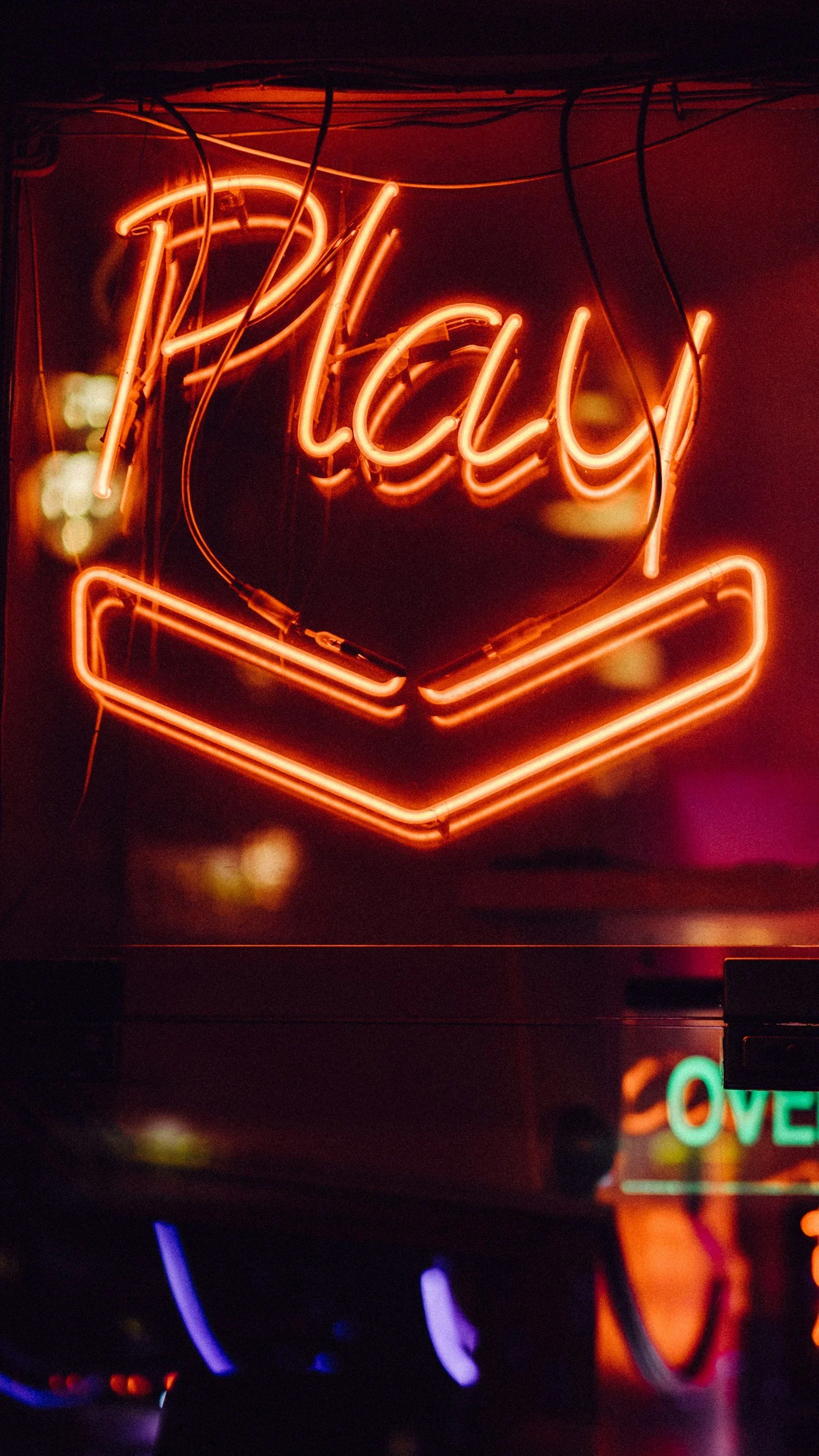 A neon sign with the word 'Relax' written in orange cursive, with a heart shape and an open book underneath, illuminated in a dark setting.