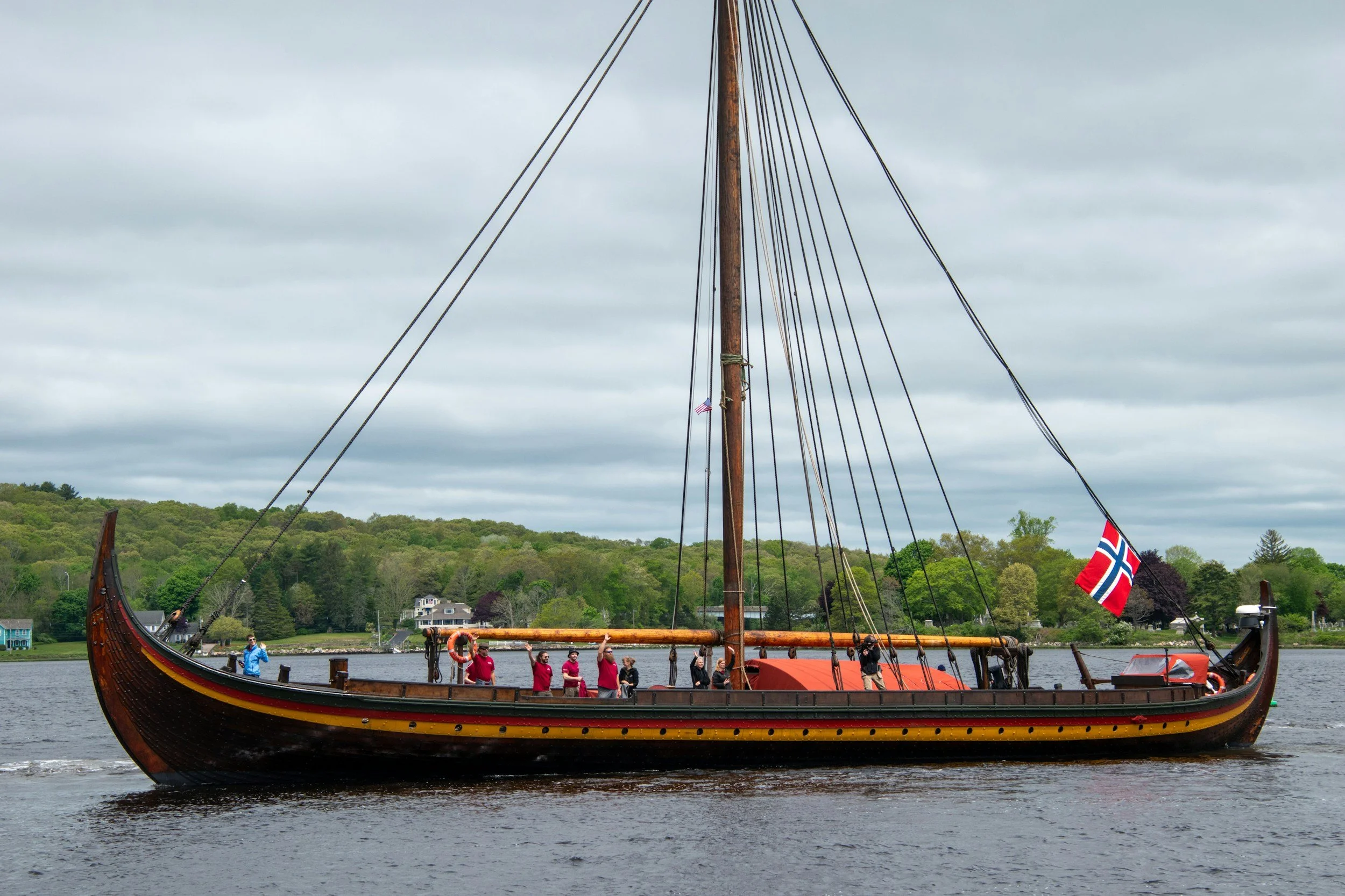 Viking ship filled with a joyful community, rowing together across the fjord. A happy community, rowing in unity through a Scandinavian fjord.