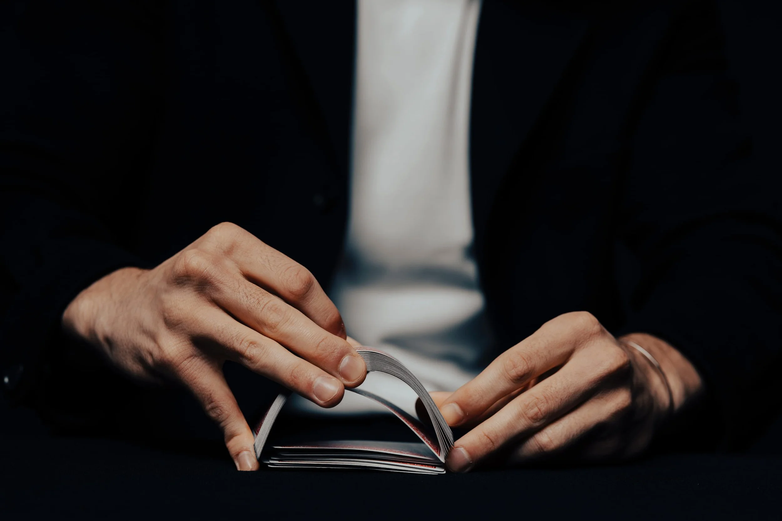 A person in a dark suit and white shirt is holding and reading a small booklet or catalog, with their hands visible.