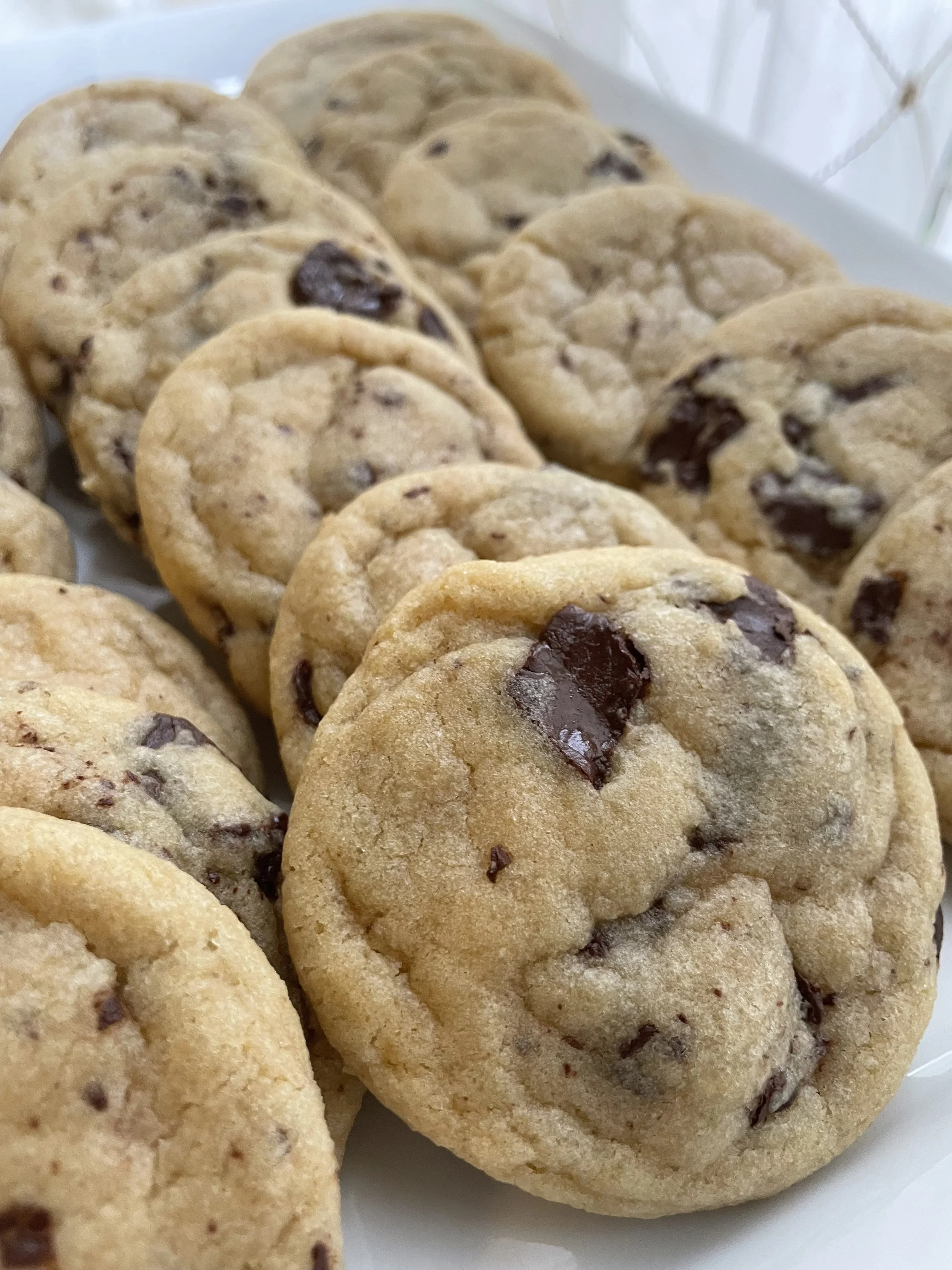 Close-up of several chocolate chip cookies on a white plate.