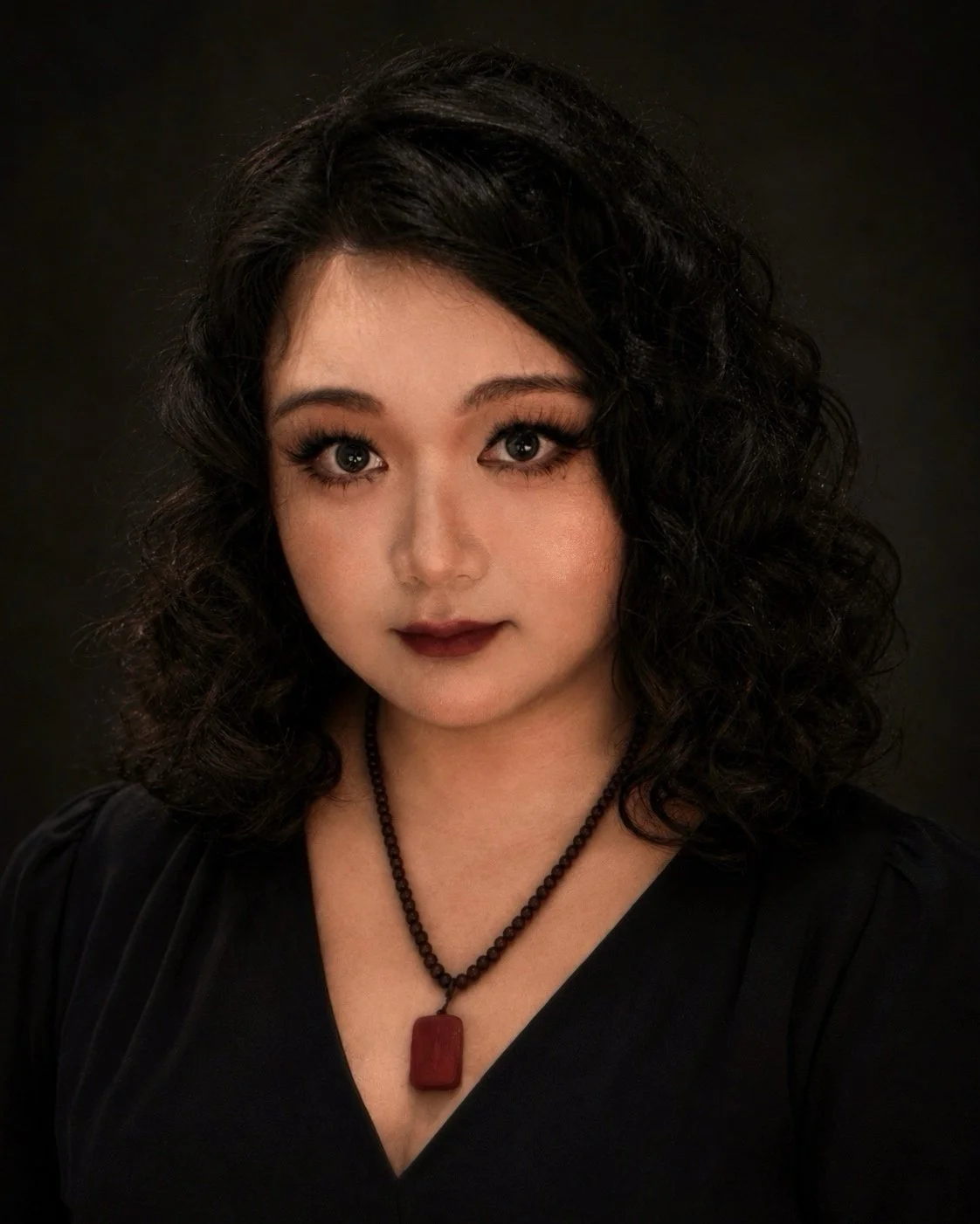 Portrait of Cassie Xue, a writer, playwright, dramaturg, theatre critic and researcher, against a dark background.
