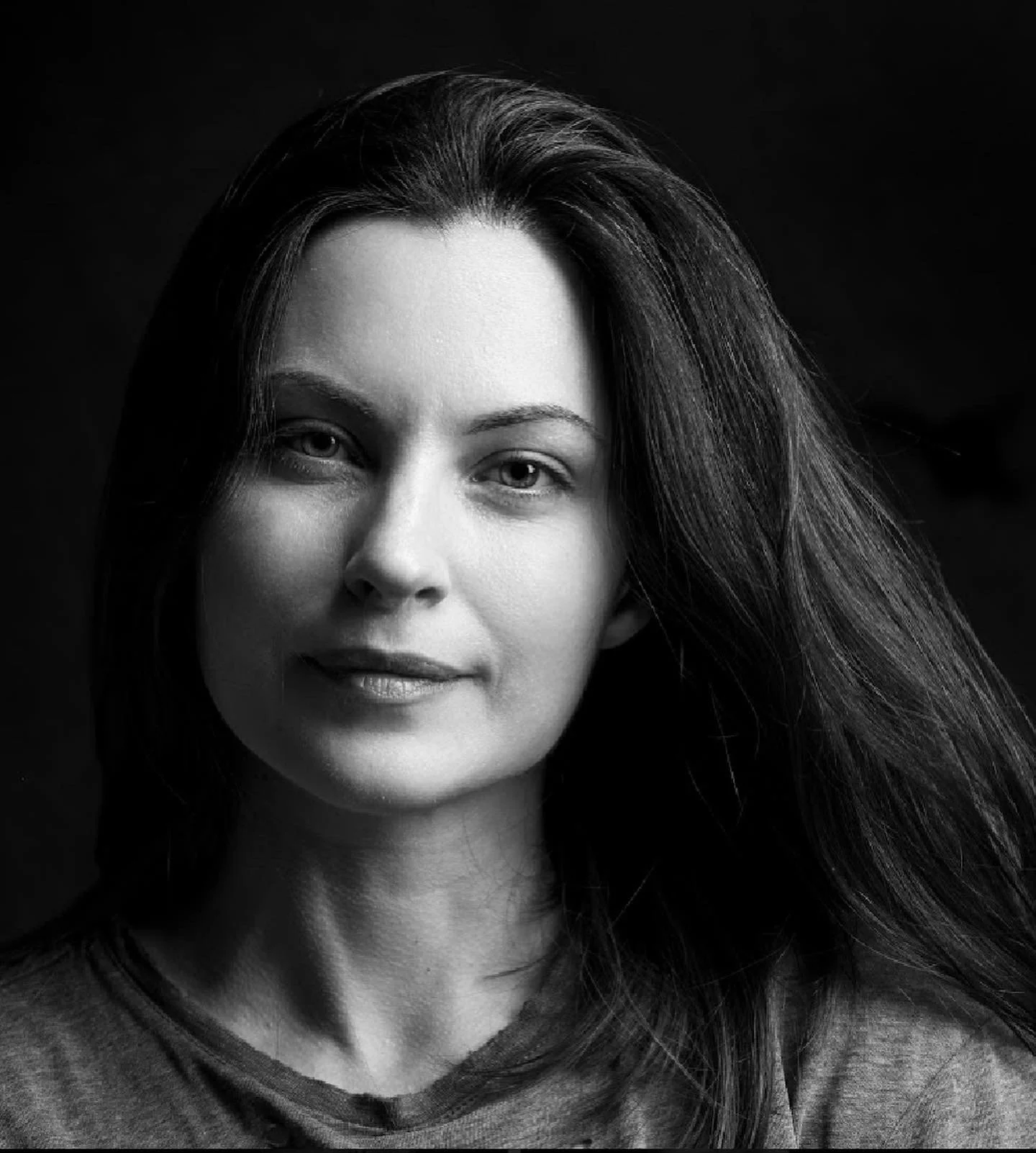 Black and white portrait of a woman with long hair, looking at the camera with a slight smile.