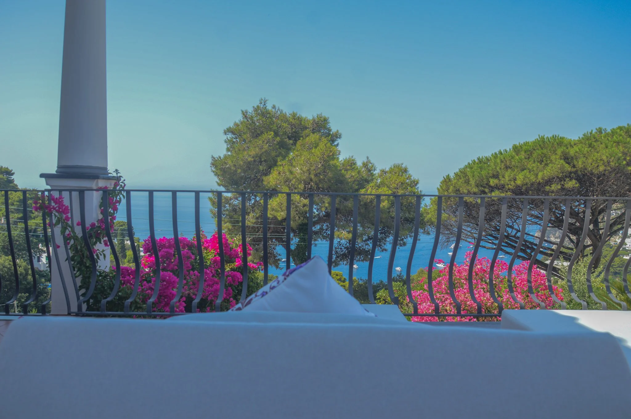 Spacious sun terrace with blue loungers and vibrant bougainvillea at a Capri sea view accommodation.