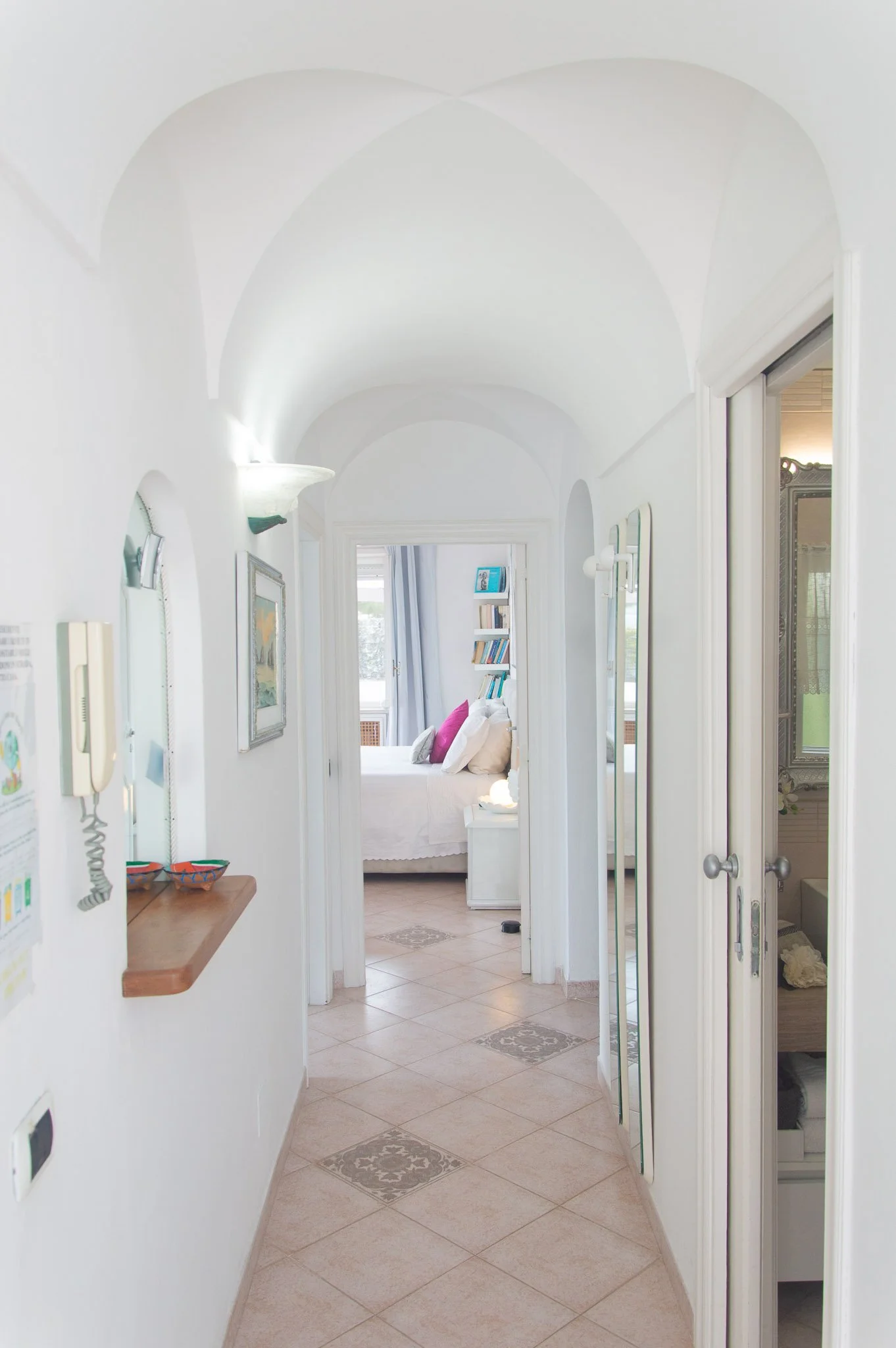 Bright villa hallway featuring a colorful Capri painting on the wall leading into a sea view bedroom.
