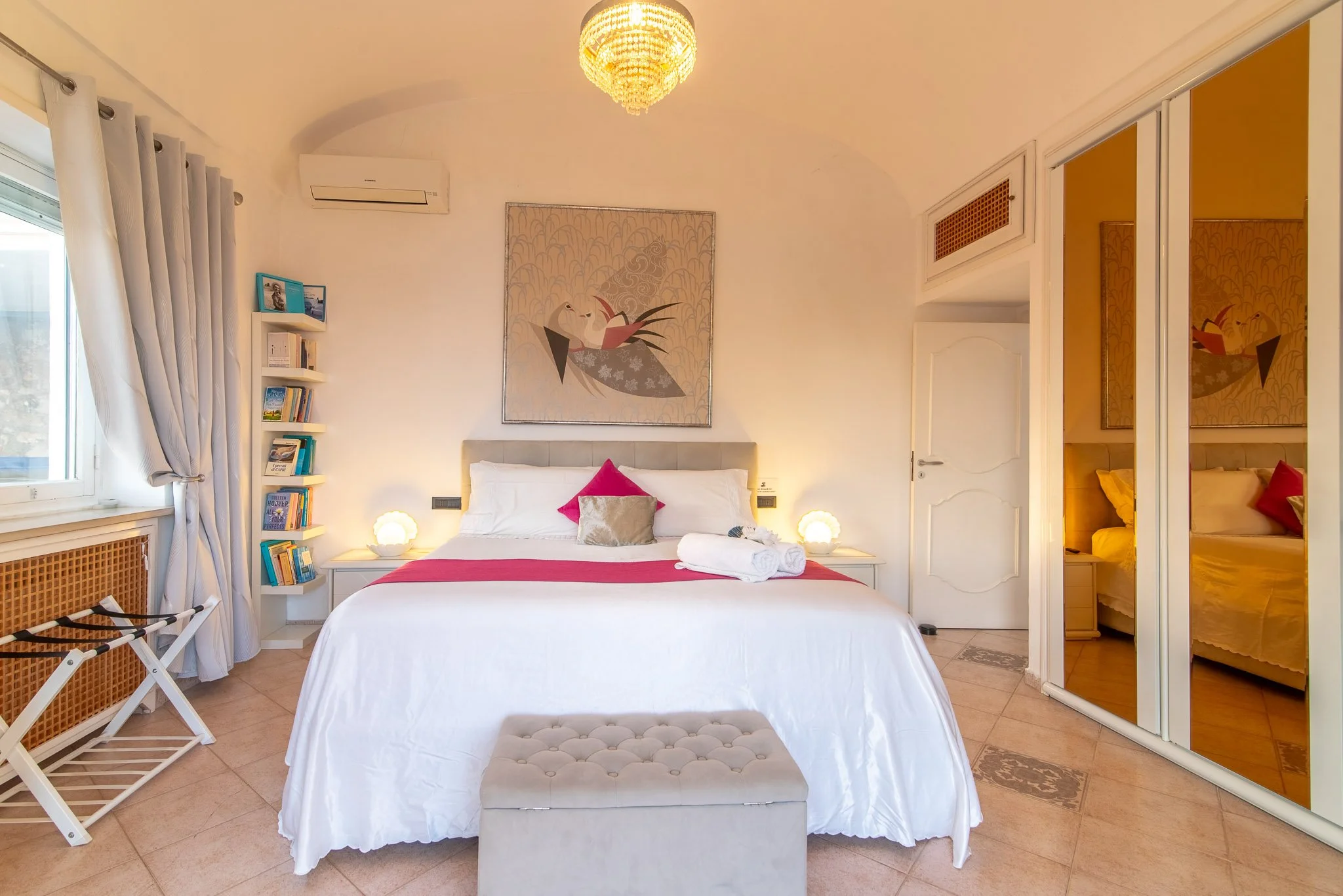 Elegant crystal chandelier hanging above a stylized bird artwork inside a luxury Capri accommodation.