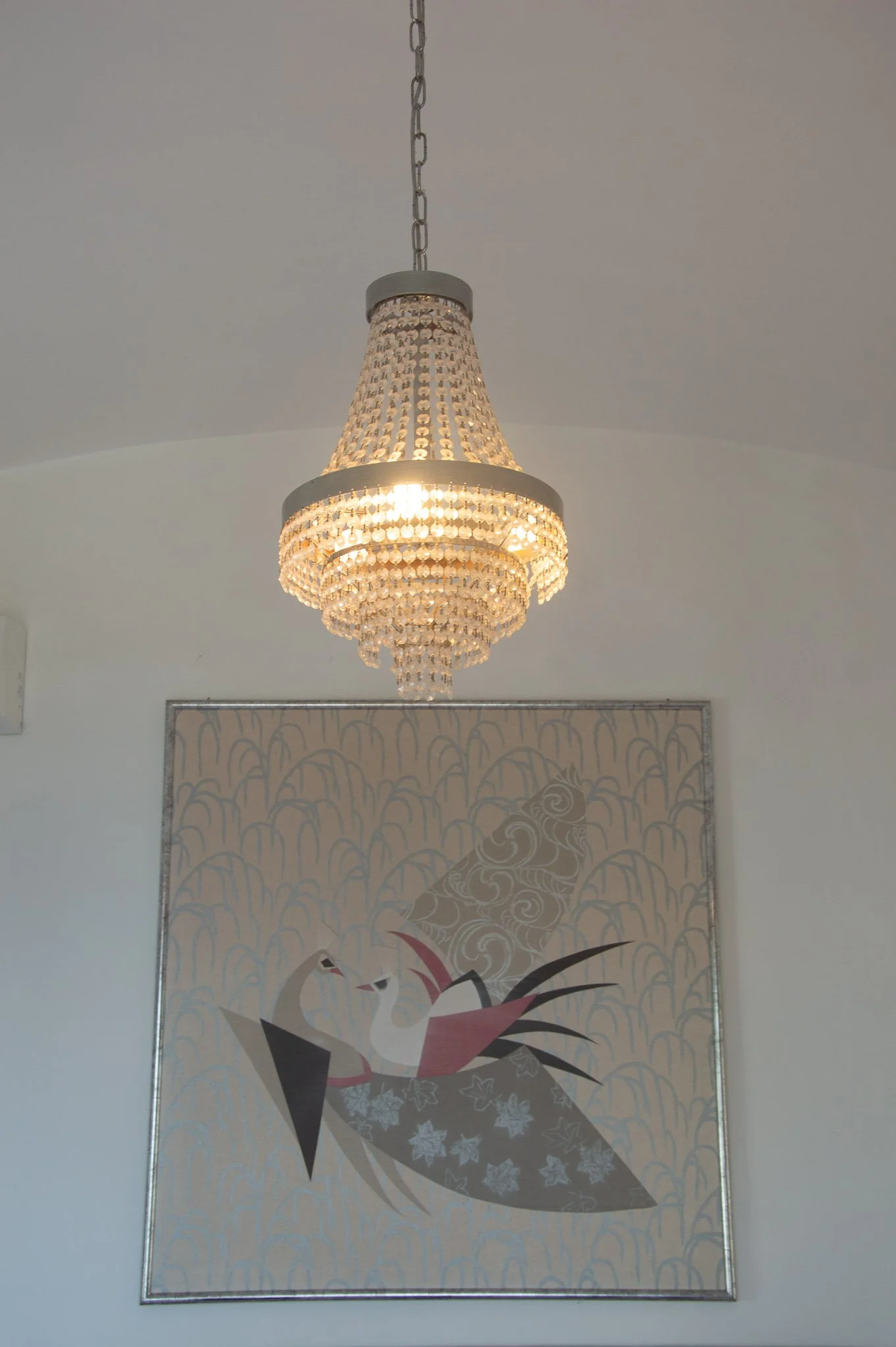 Luxurious crystal chandelier hanging above a stylized bird artwork inside a Capri accommodation.