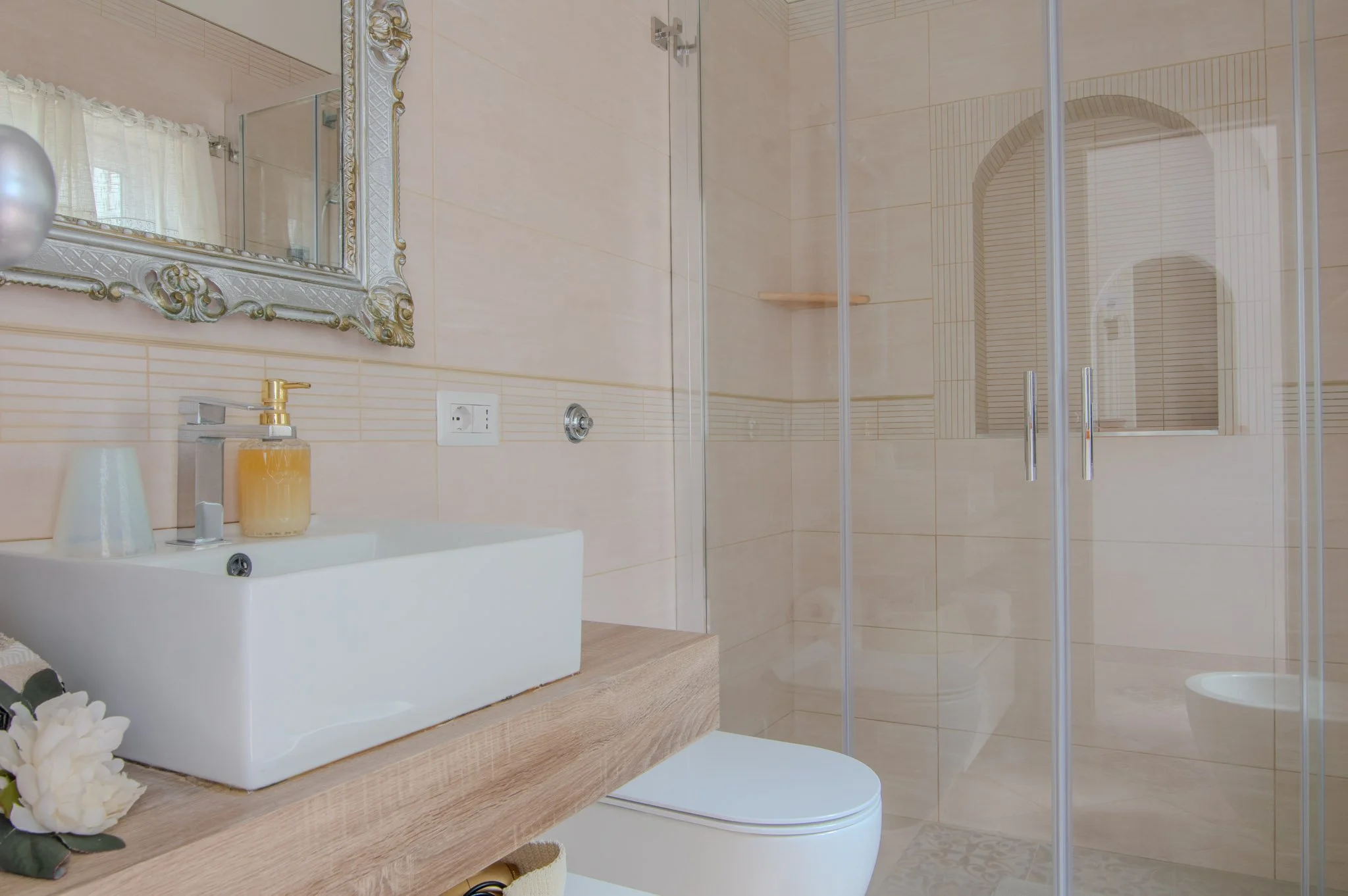 Clean bathroom interior showing a wooden vanity counter and glass shower enclosure inside the villa.