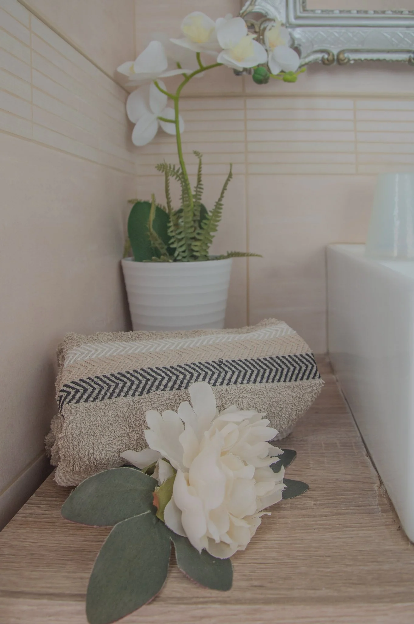 Soft guest towels paired with white orchid decor on a wooden bathroom counter.