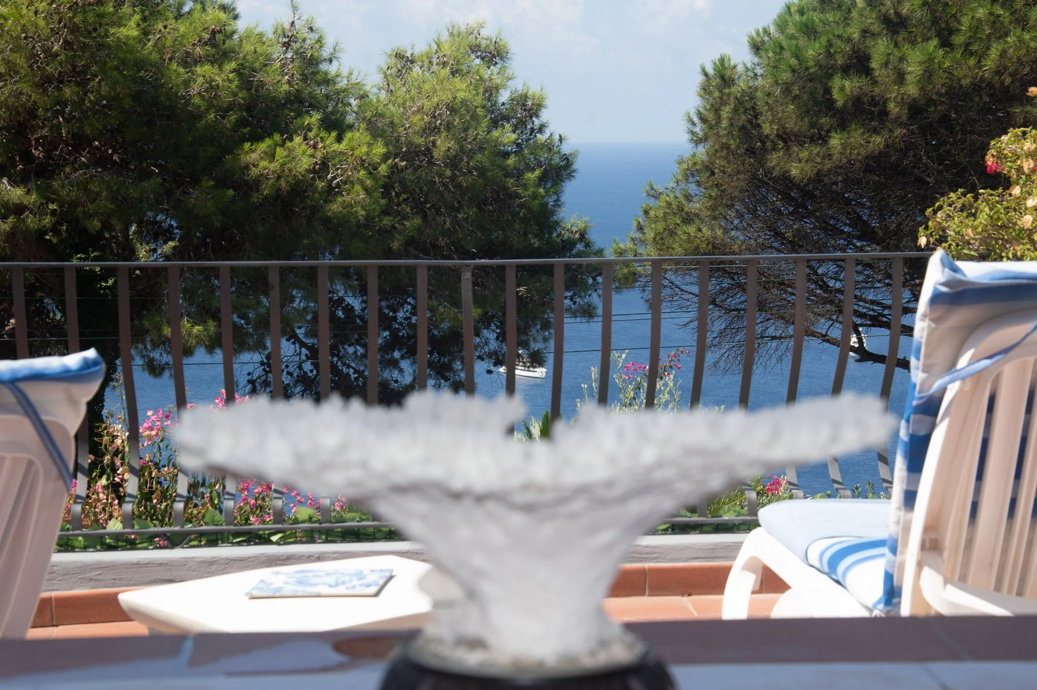 Scenic terrace table styled with a decorative white coral piece at an upscale Capri boutique stay.