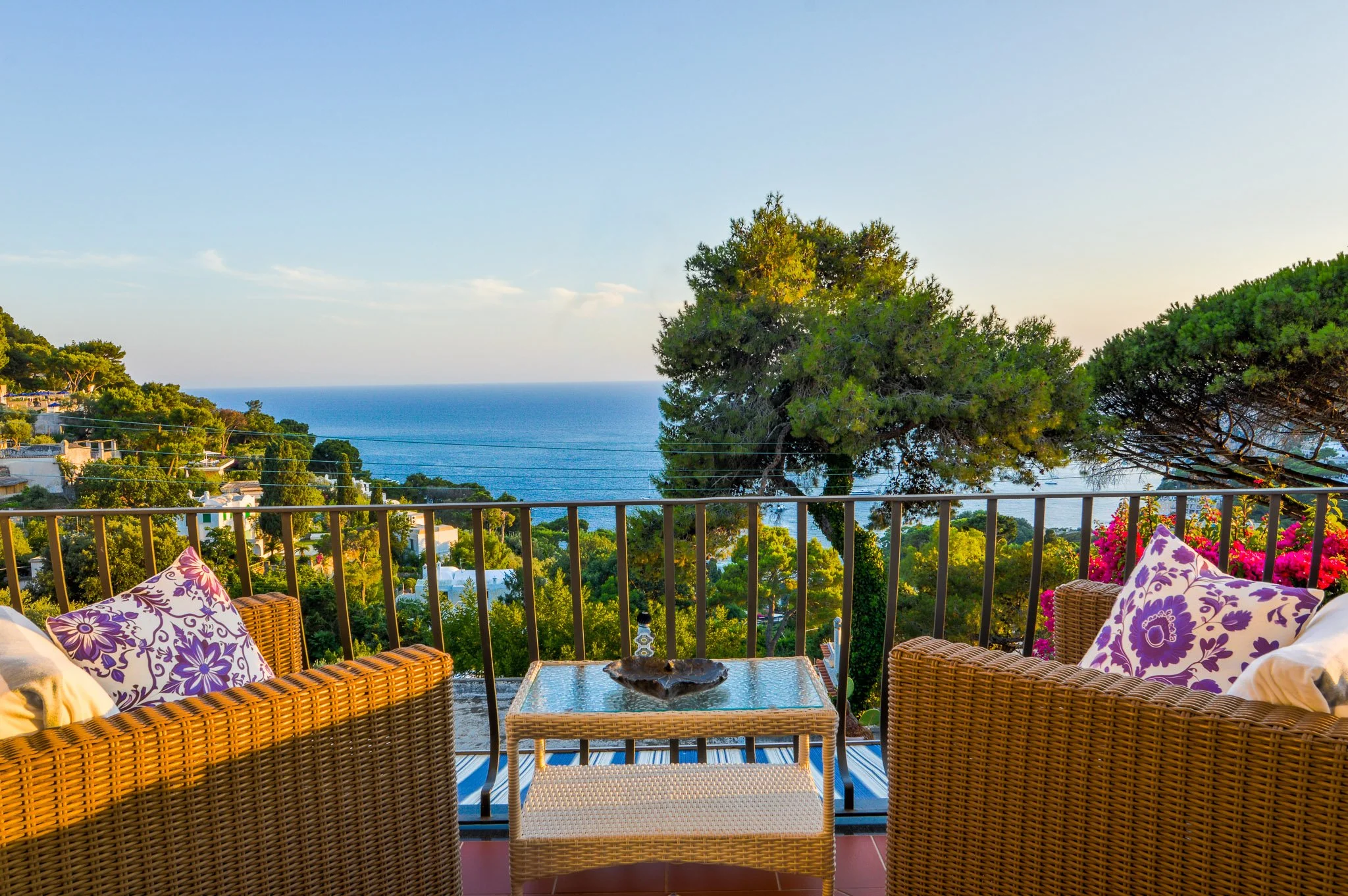 Comfortable outdoor lounge area with woven armchairs overlooking the blue sea of Marina Piccola.
