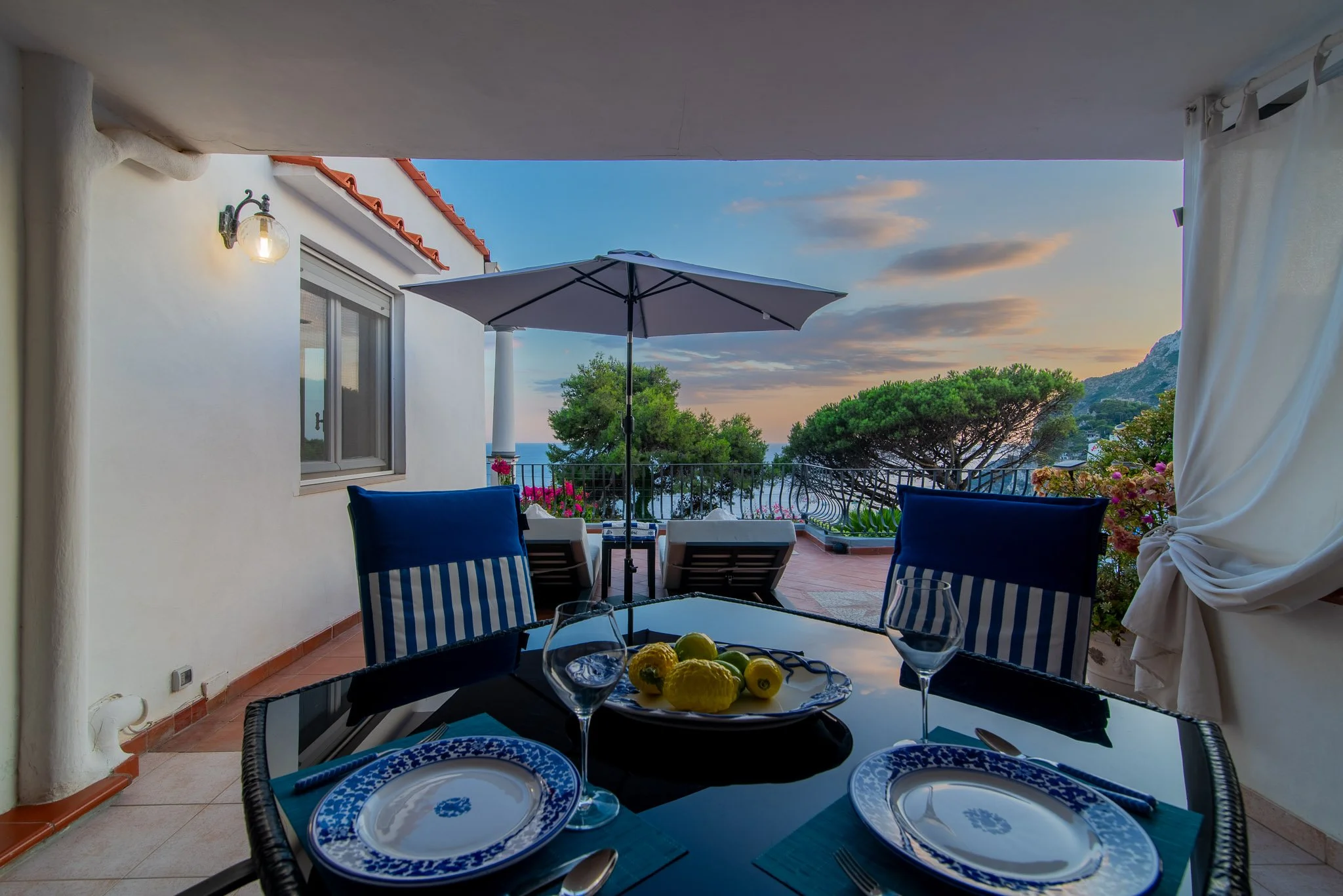 Al fresco dining table set with Mediterranean style plates at a premium Capri vacation rental during sunset.