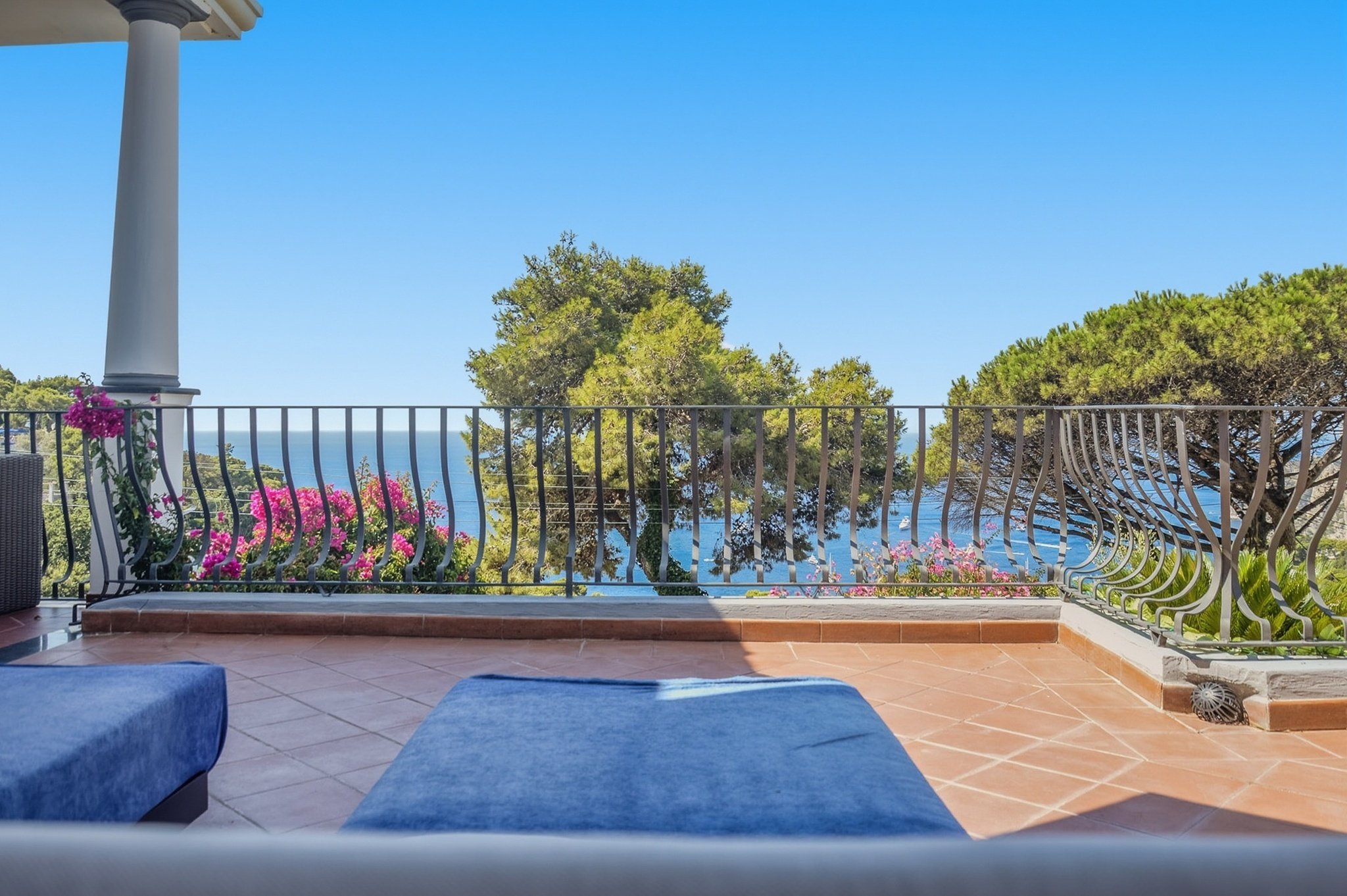 Sunny sunbathing terrace with blue loungers and sea views at a Capri vacation rental Penthouse.