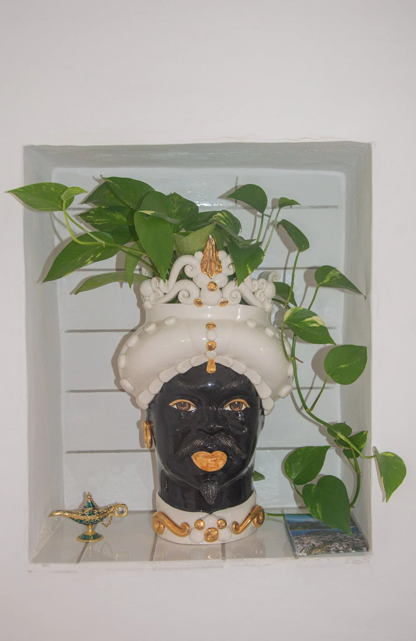Traditional ceramic Moorish head vase with a green plant inside a wall niche at Marvelous Capri stay.