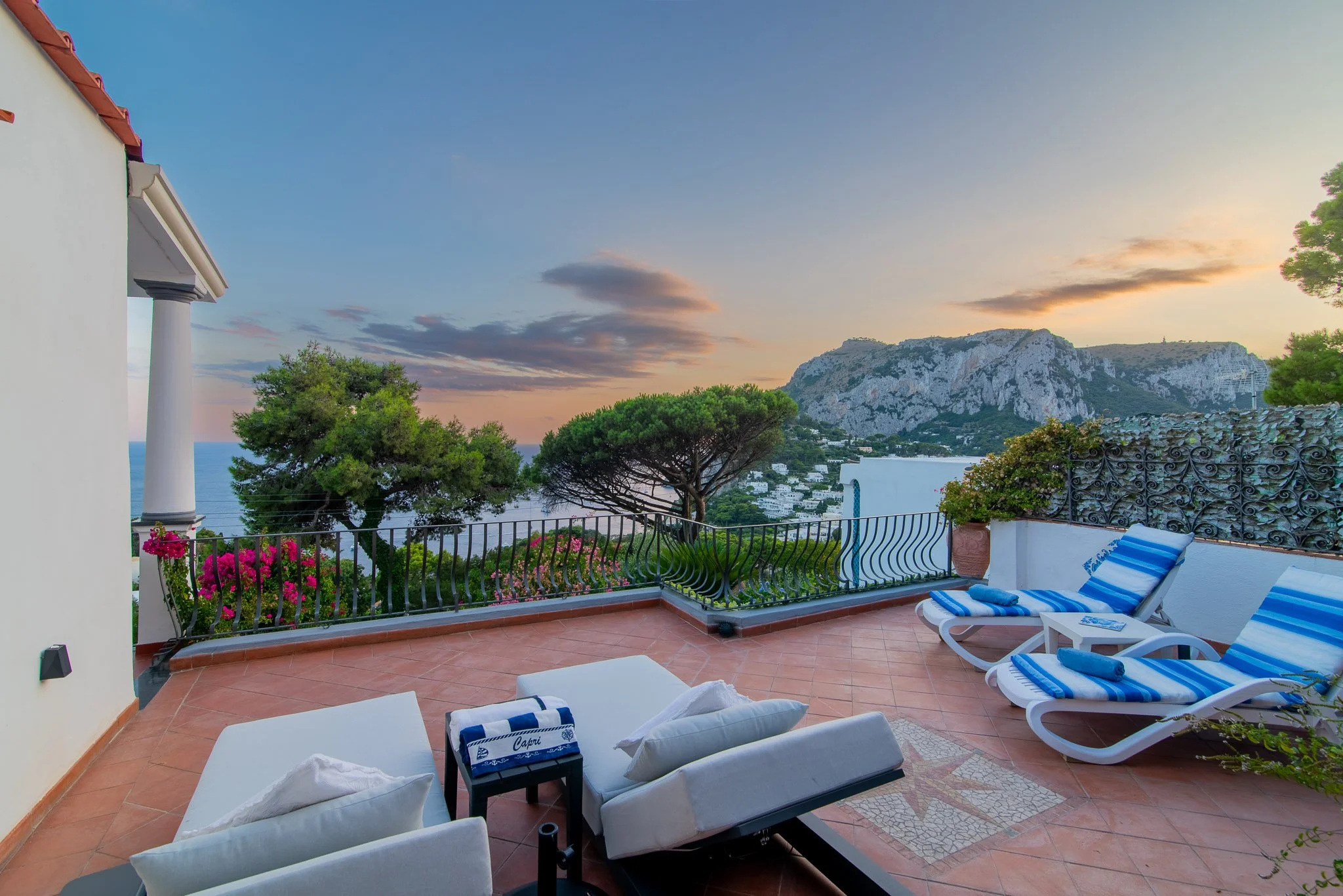 Sun terrace with comfortable loungers overlooking the dramatic cliffs and coastline at a Capri holiday accommodation.