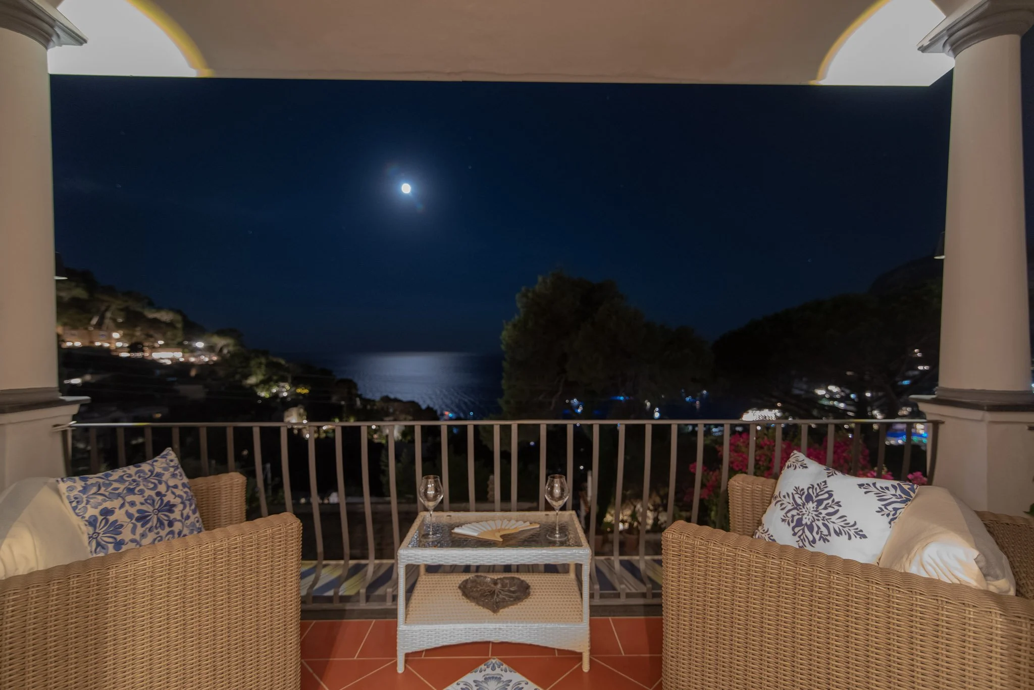 Romantic night view of the illuminated Capri coastline under full moonlight from a private balcony.