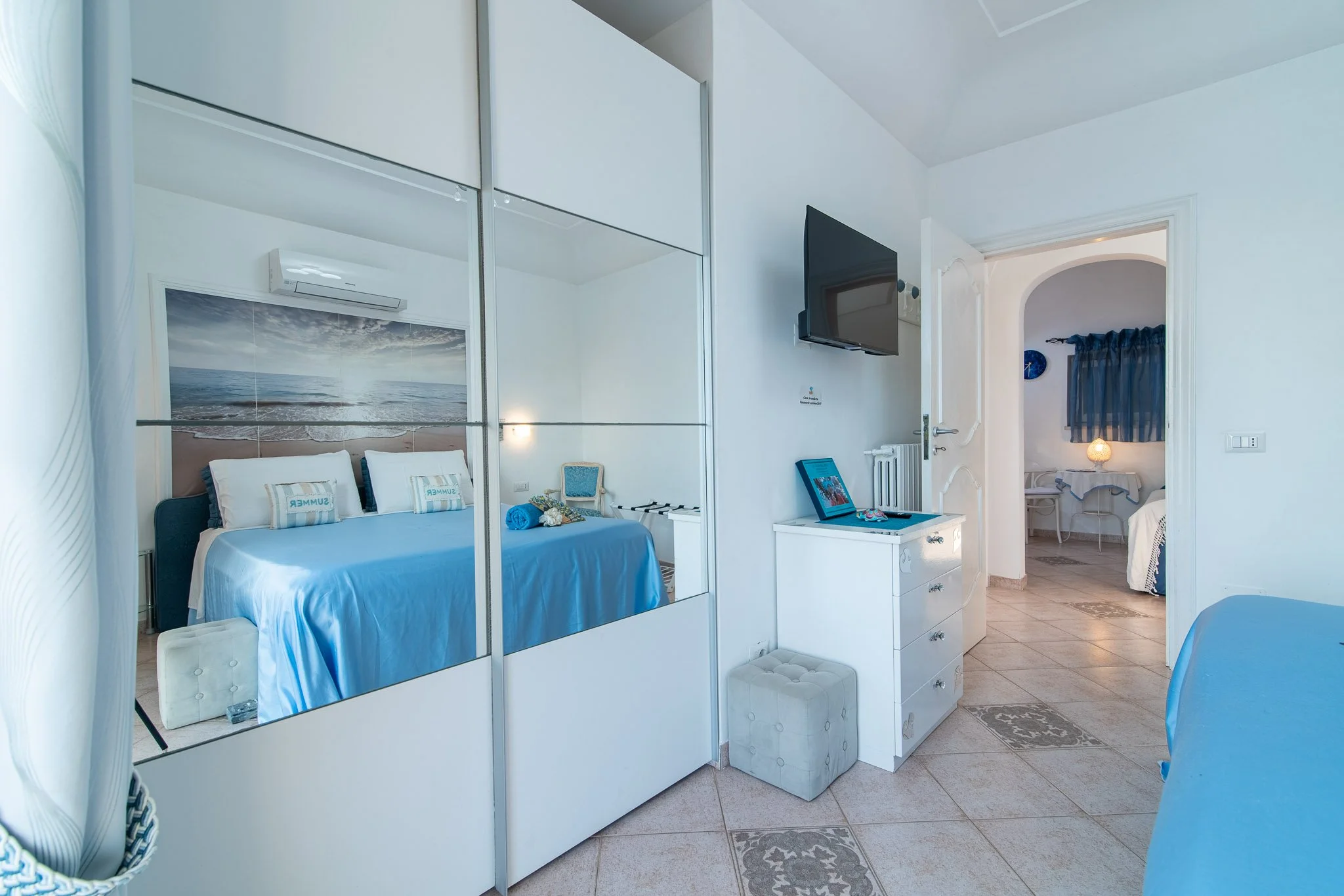 Elegant guest bedroom at Marvelous Capri villa featuring a blue bed setup and mirrored wardrobe.