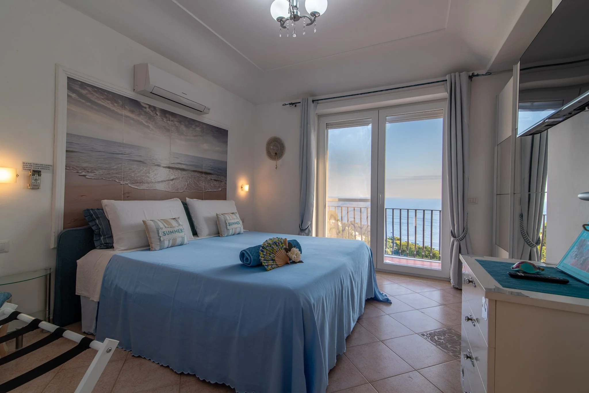 Elegant guest bedroom at Marvelous Capri penthouse with marine blue decor, a large beach mural, and a balcony facing the sea.