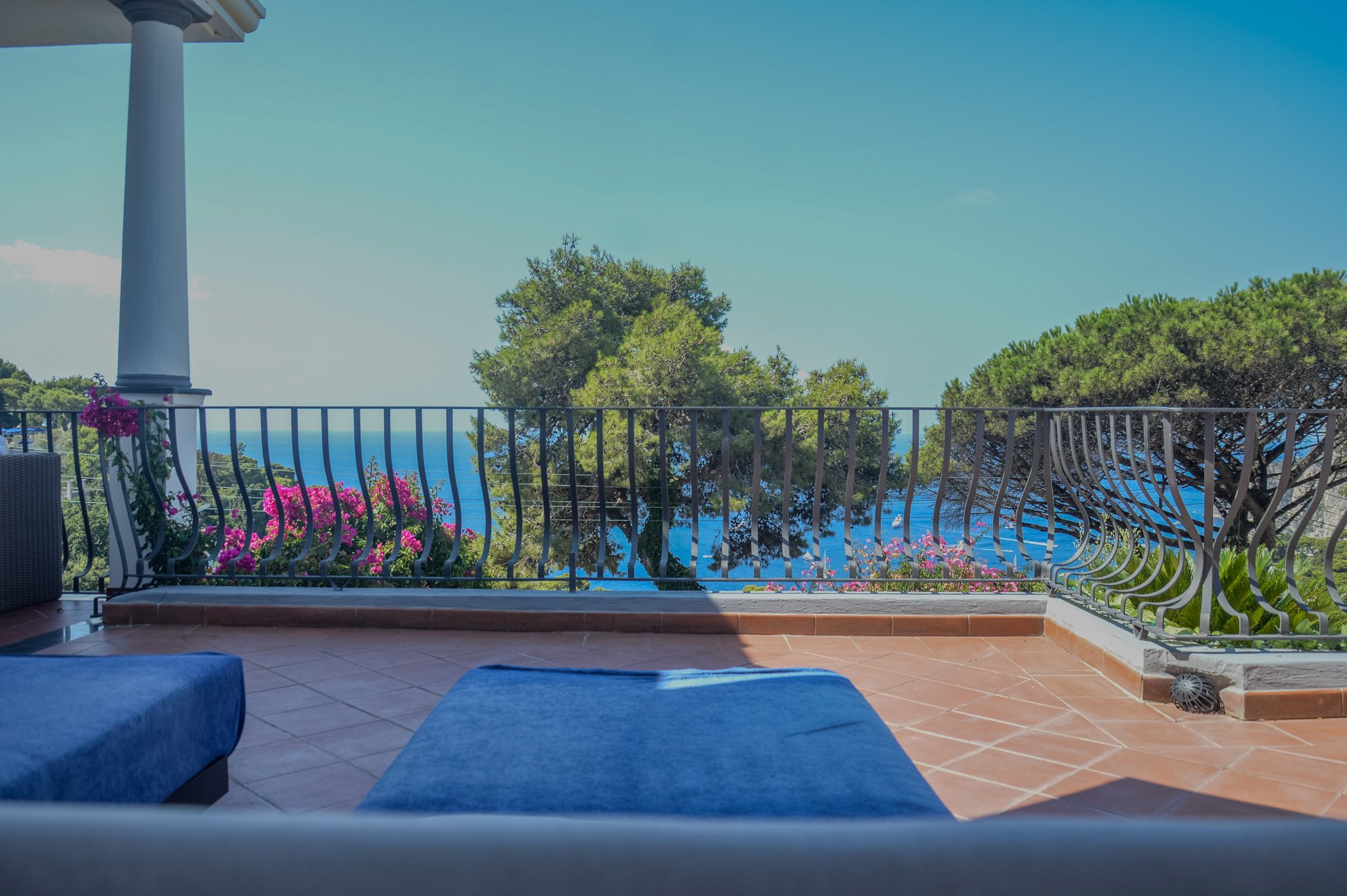 Sunny sunbathing terrace with blue loungers and sea views at a Capri vacation rental Penthouse.