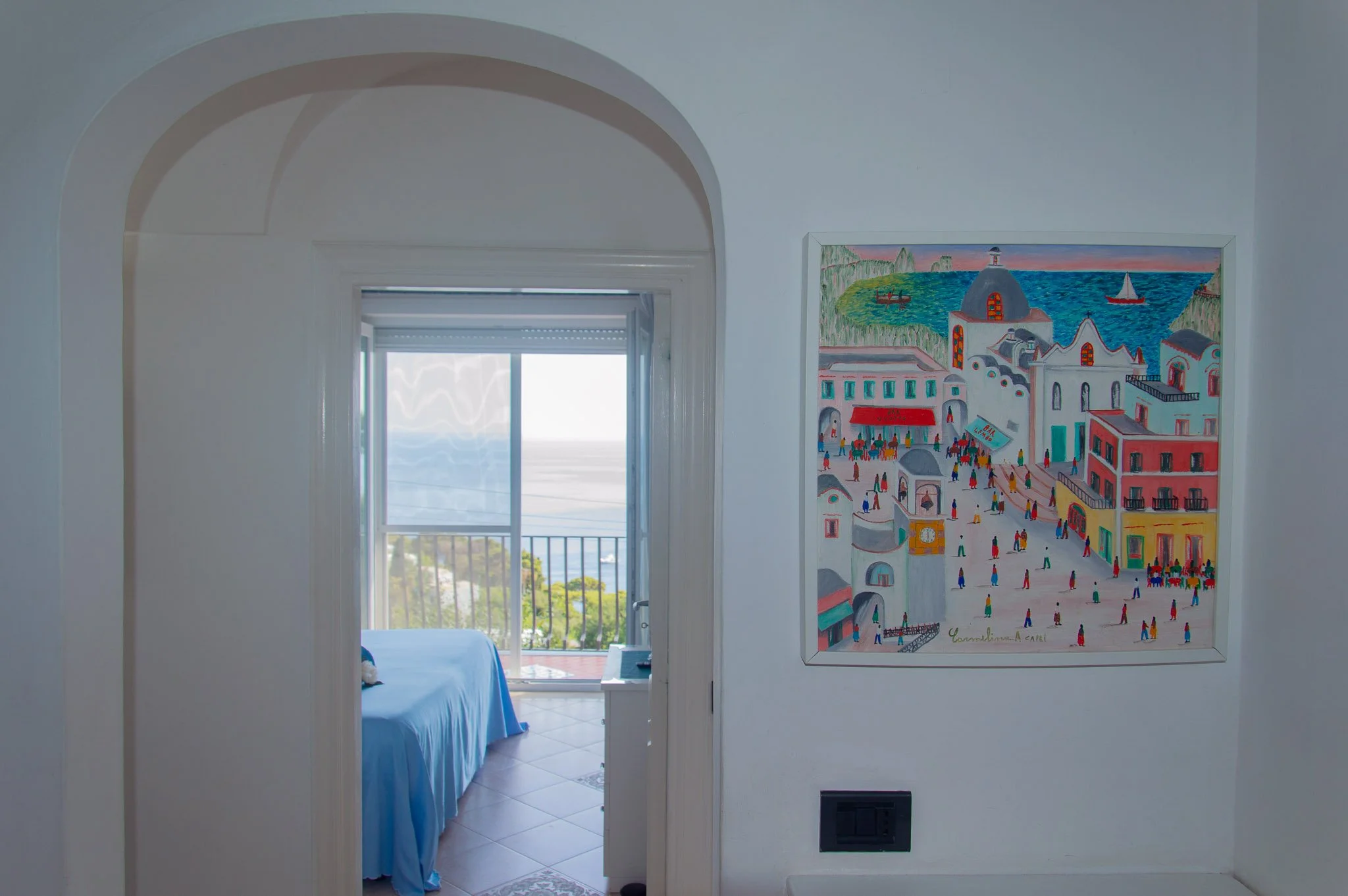 Mediterranean villa hallway with a colorful painting of Capri Piazzetta looking into a sea view bedroom