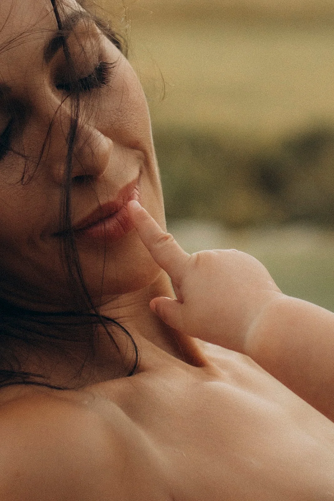 Close-up of a woman with closed eyes touching her lips with her finger.