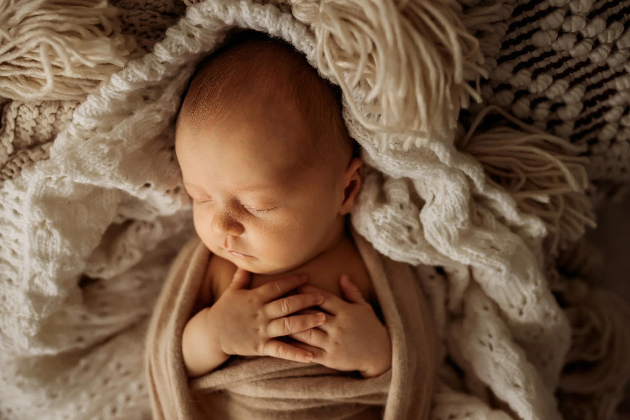 Close-up of a sleeping baby wrapped in a cozy, knitted blanket.