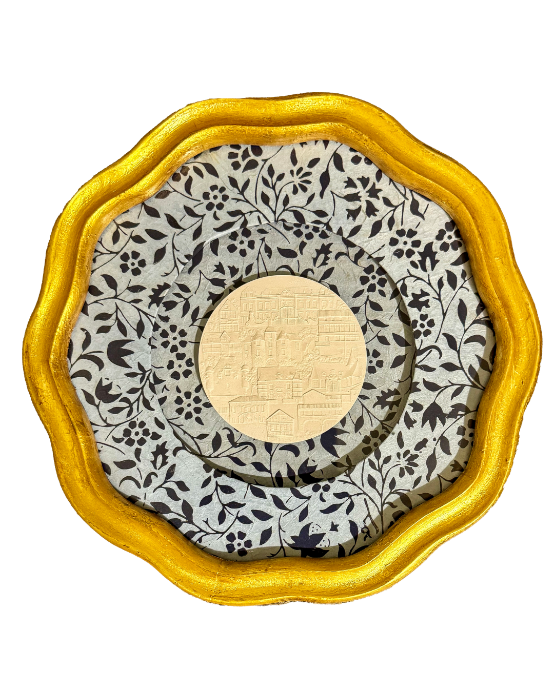 Decorative tray with a gold-colored, wavy edge, patterned black and white floral paper lining, and a centered gold medallion with embossed cityscape design.