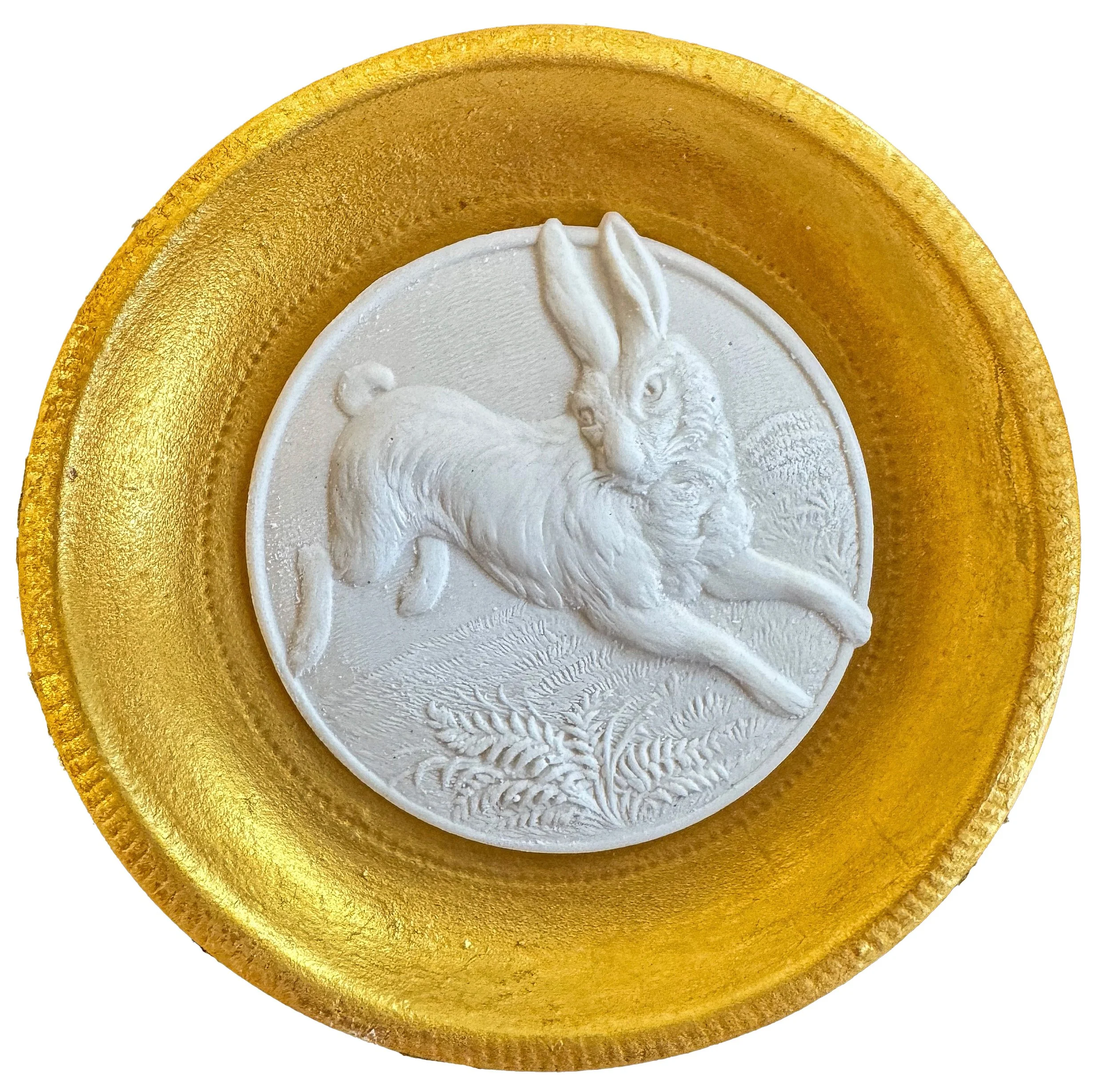 Close-up of a gold-colored circular object with a white spiral design in the center and a textured rim.