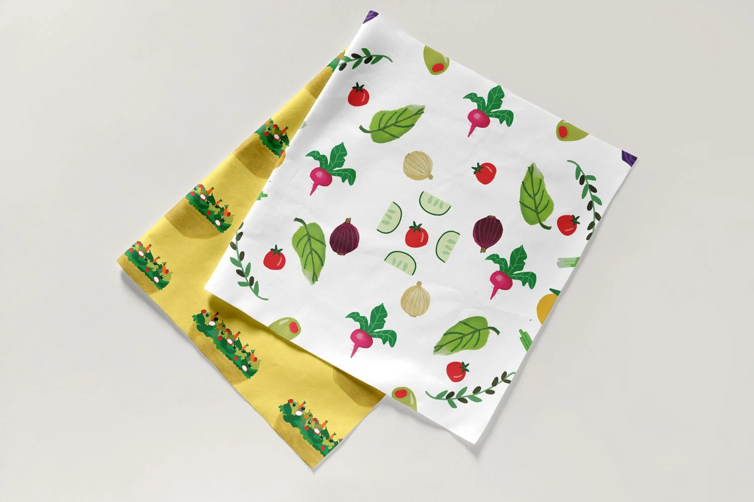 Two swatches of fabric with salad patterns on them -  one with yellow background and the other with white background.