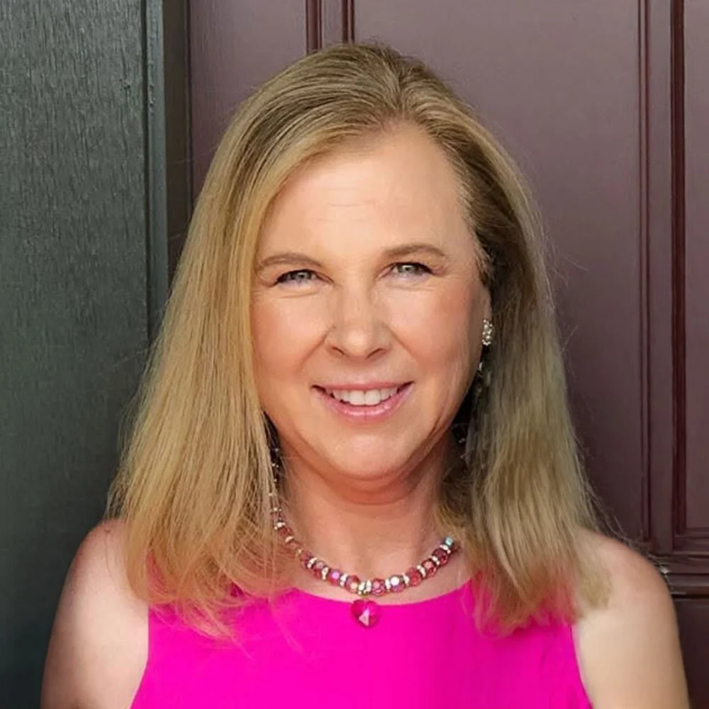 A headshot photo of artist Victoria Louise Rudolph in a pink top.