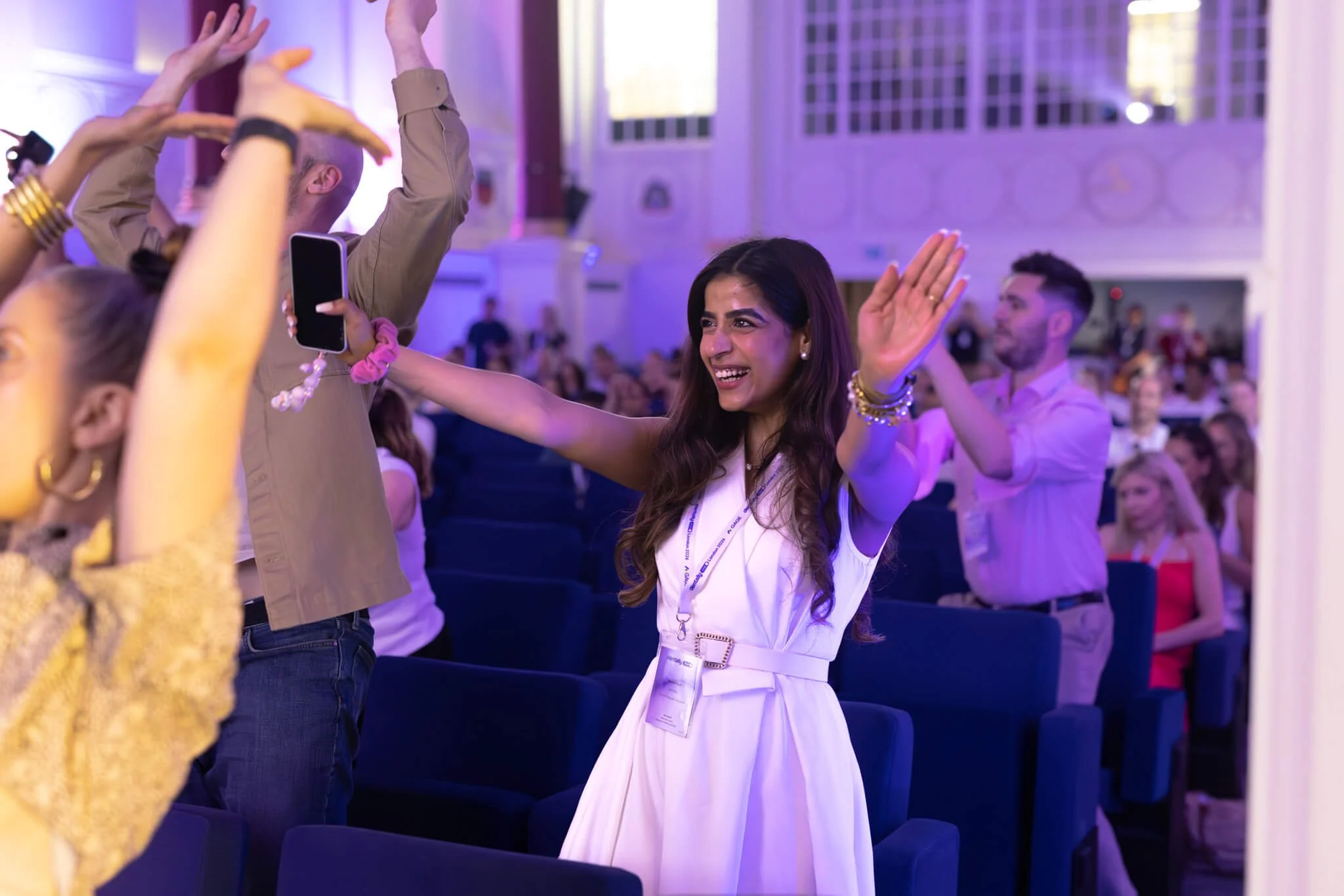 A woman in the crowd at a conference completes a Mexican wave
