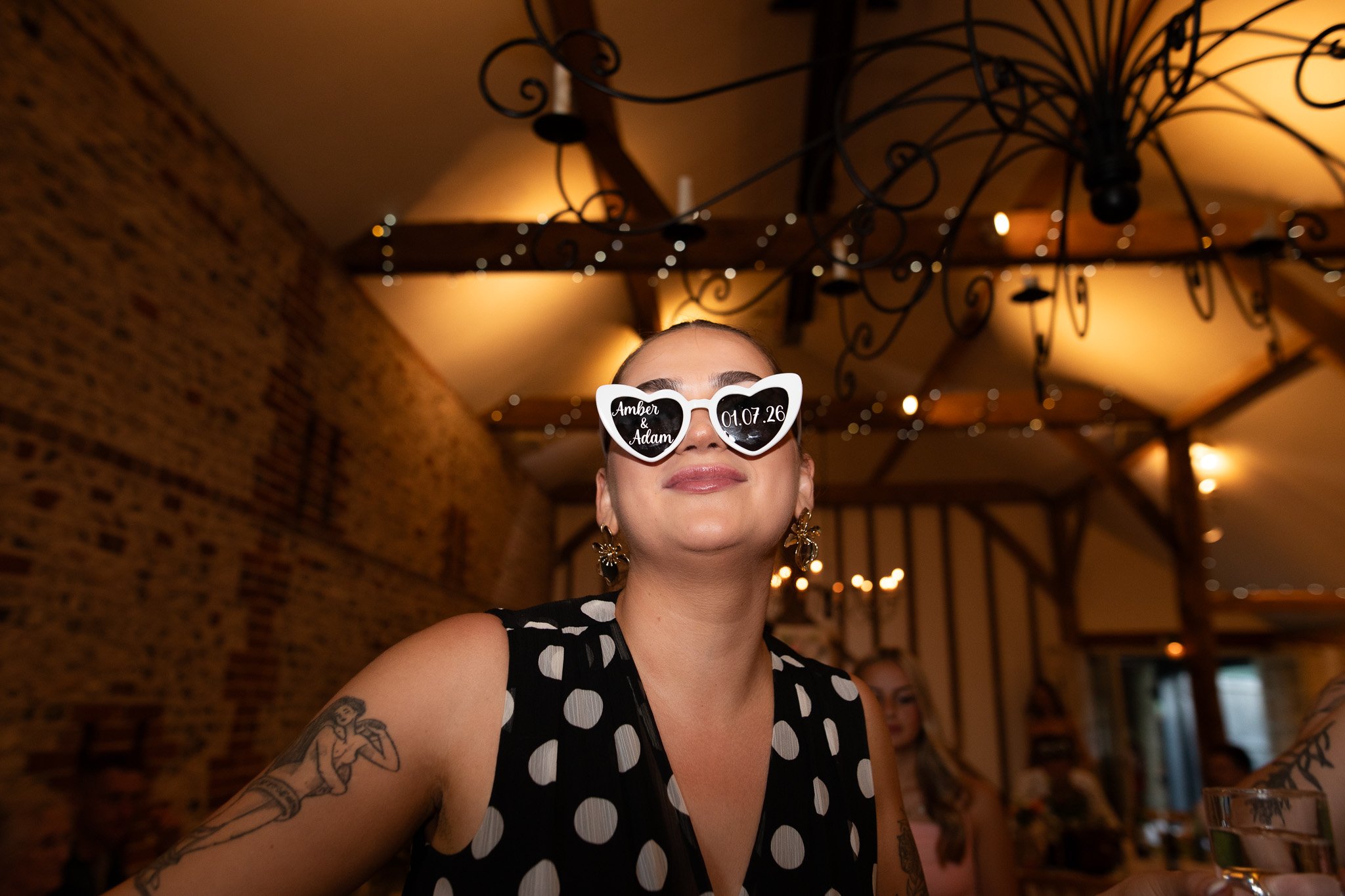 A guests dances at upwaltham barns whilsts wearing custom glasses with the bride & grooms name and wedding date on