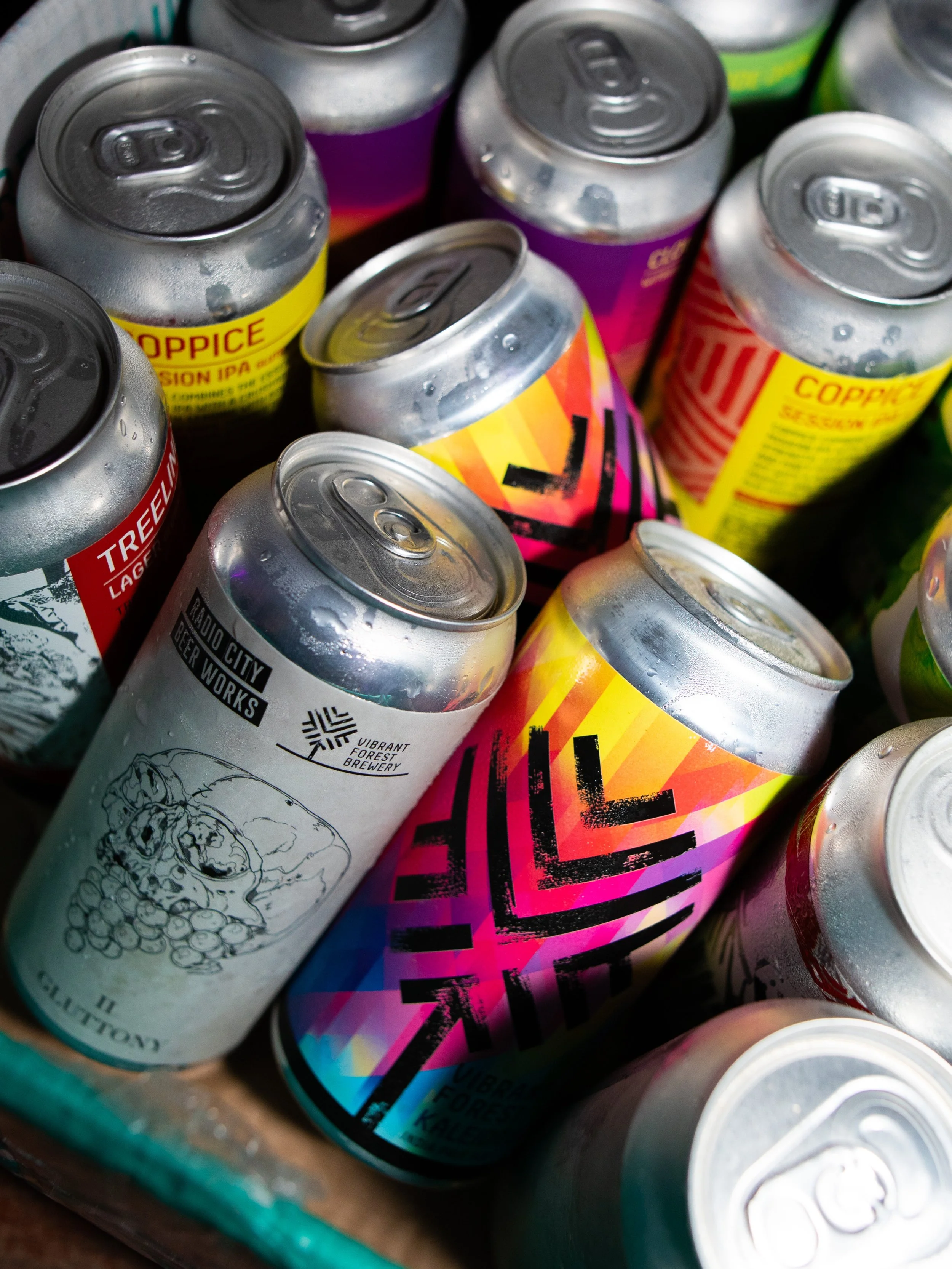 A close-up view of colorful cans of various beverages with condensation on their surfaces.