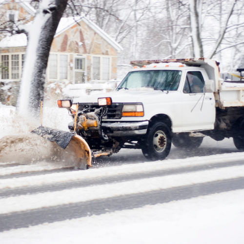 White snowplow truck clearing snow from the road in winter.
