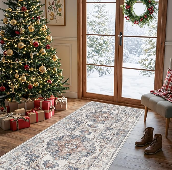 A decorated Christmas tree with presents underneath, a wreath on the glass door, and a cozy room with a view of snowy outdoors.