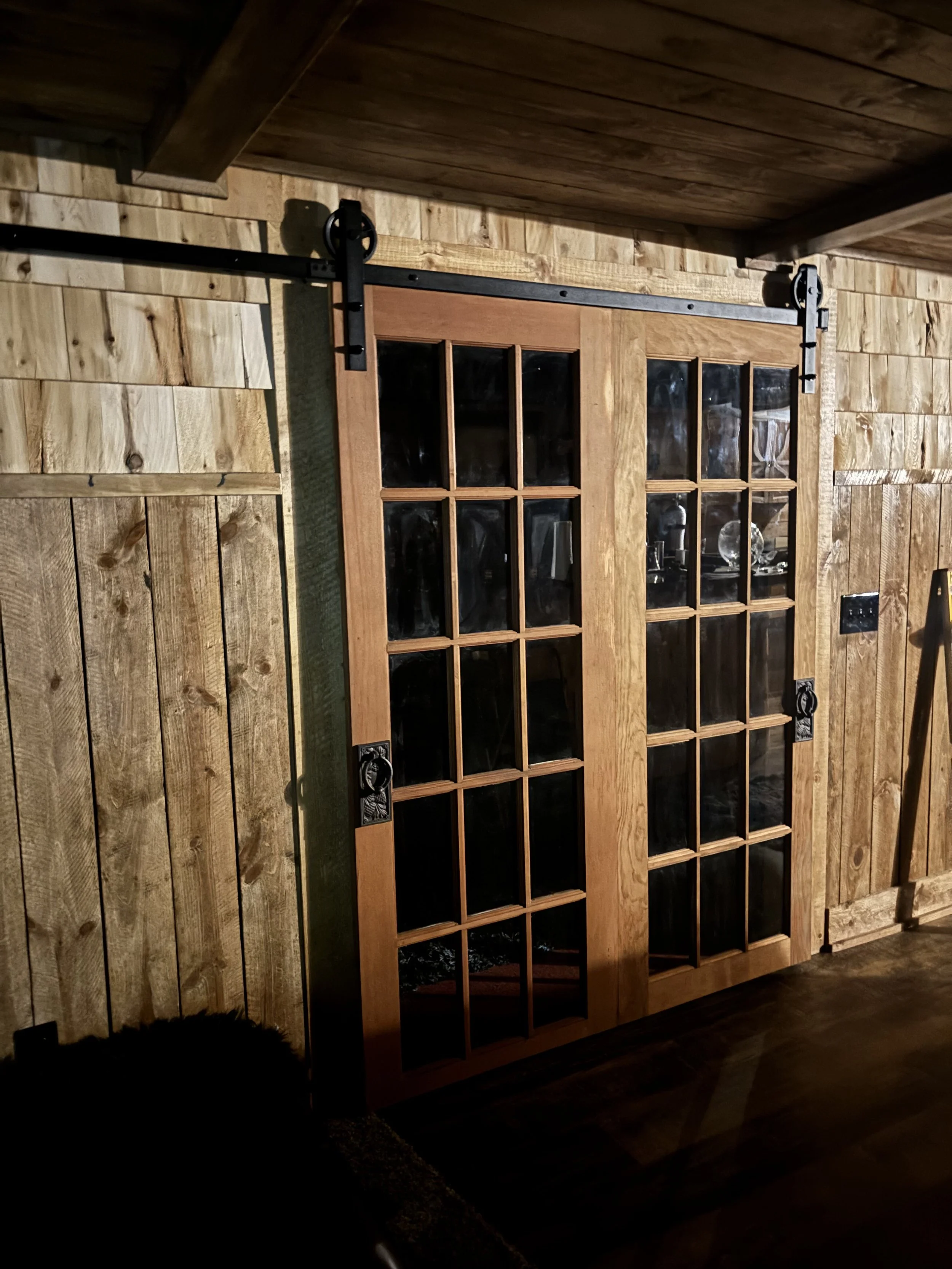 A wooden door with glass panels on a wooden wall with visible wood grain and texture.