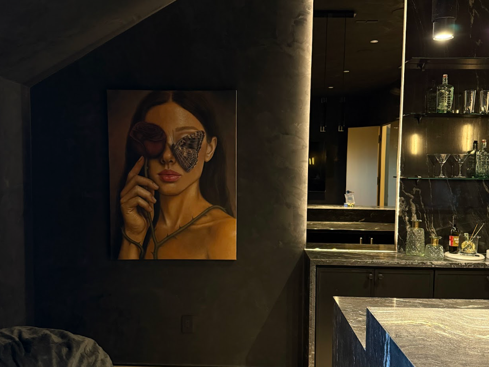 A woman with long dark hair and red lips holds her hand near her face. She is wearing sunglasses with two butterfly wings, one on each eye, and a thin strap top.Luxury art staging in Los Angeles featuring museum-quality contemporary artwork in a mode