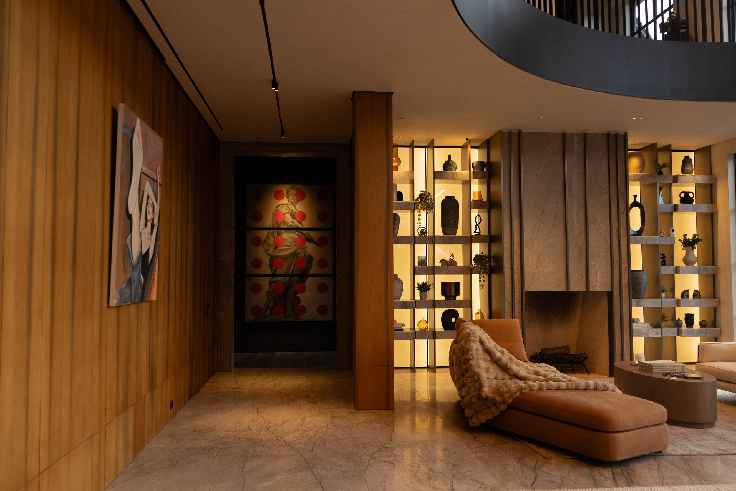 Interior of a modern living space with a wooden wall, shelves with decorative vases, a cozy beige seating area with a throw blanket, and artwork on the wall.
