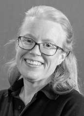 A smiling woman with glasses and wavy hair, wearing a black shirt.