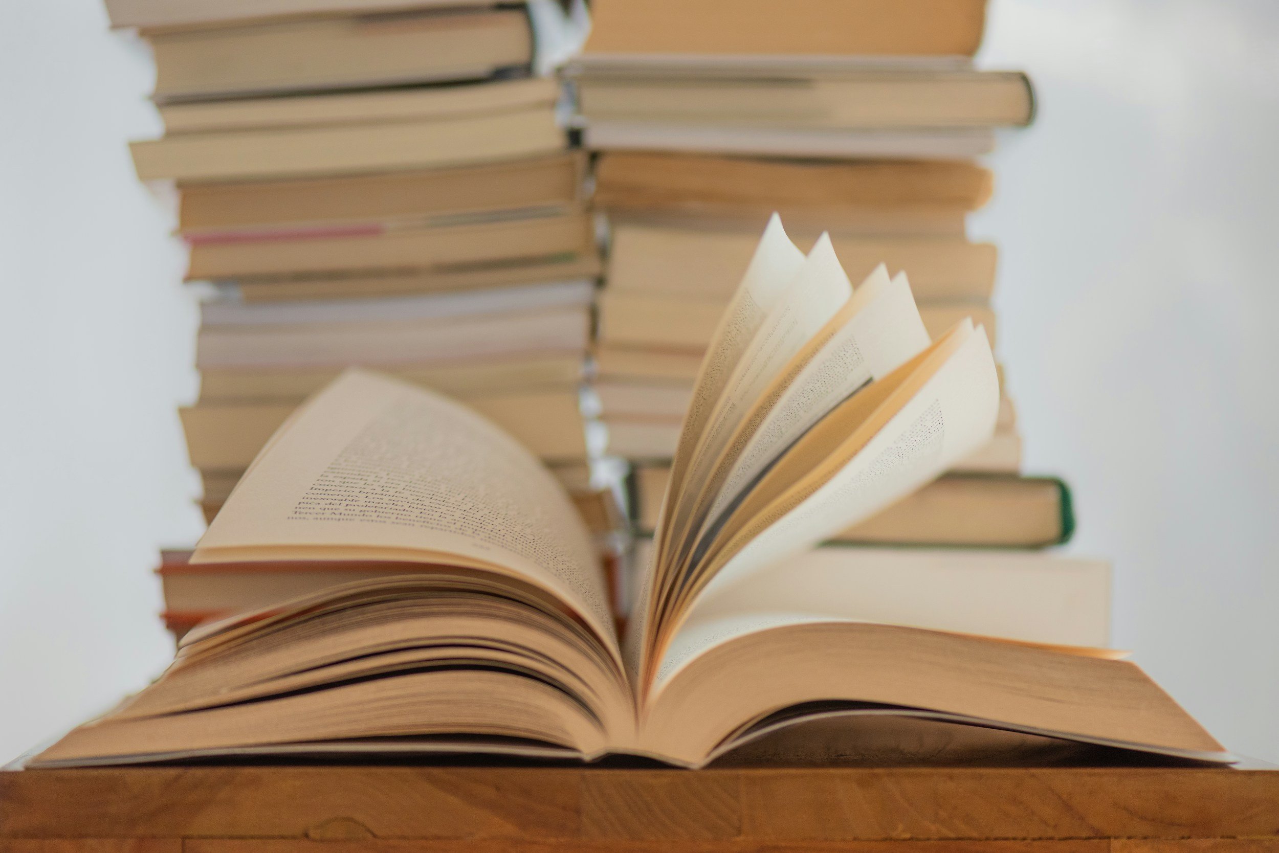 Stack of open books with pages fanned out on a wooden surface