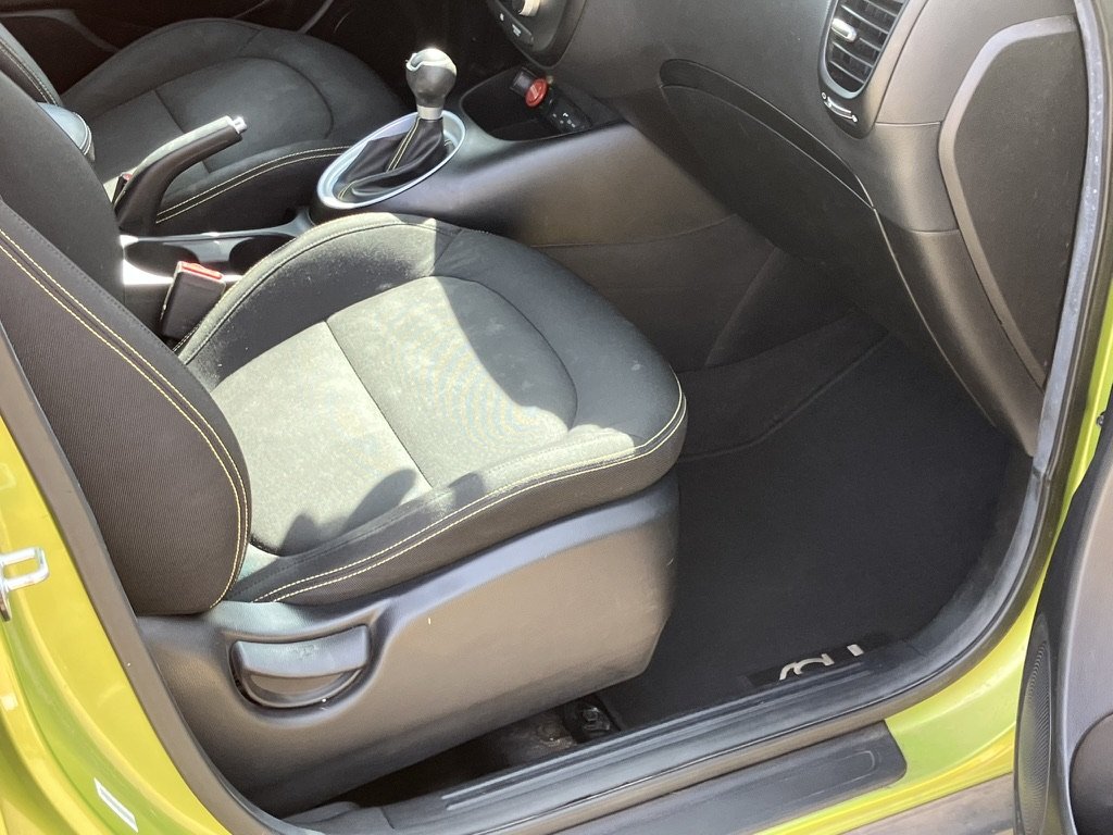The interior of a small car showing the front passenger seat, gear shift, and dashboard.