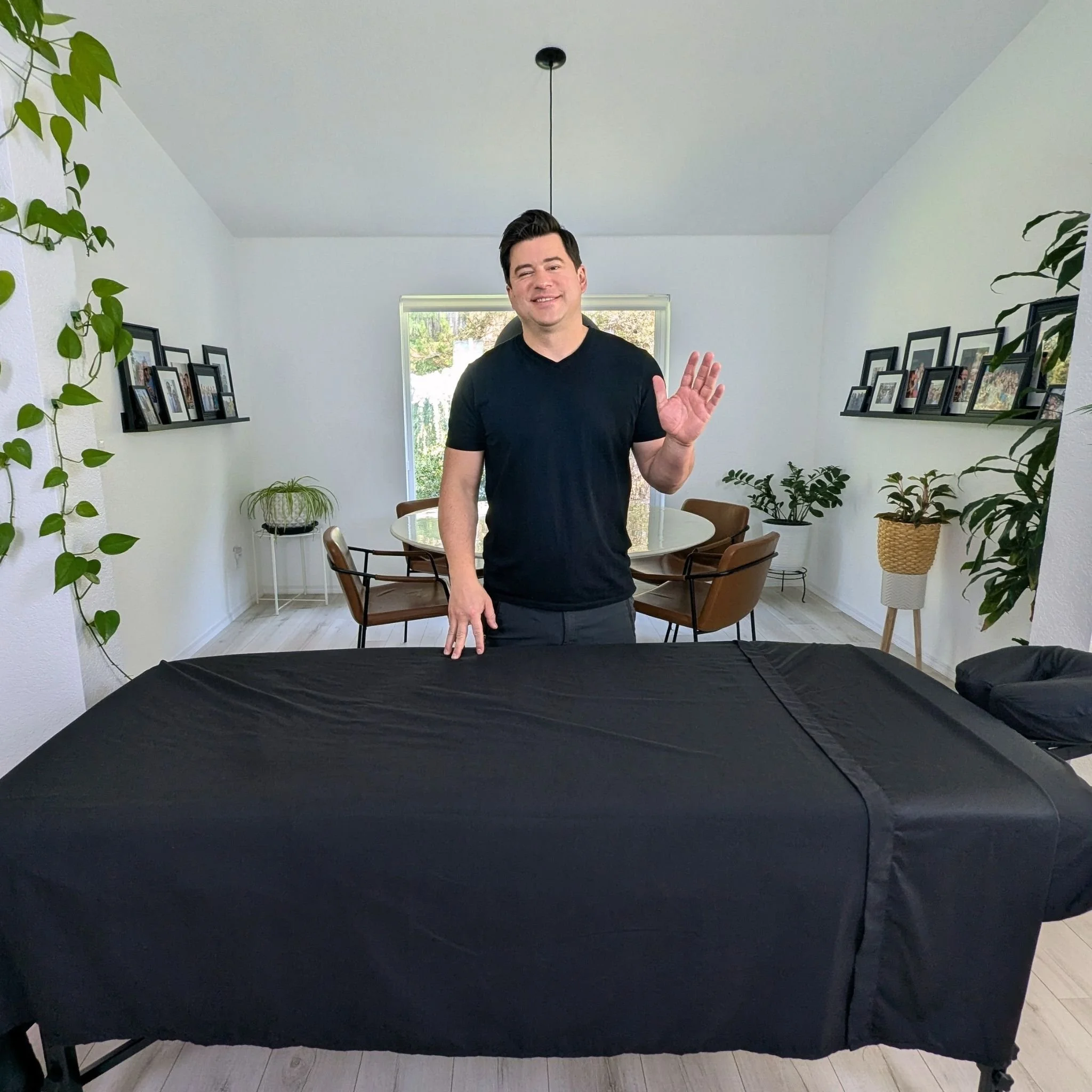 Mobile massage therapist waving next to a fully set up massage table in a Redmond client's living room.