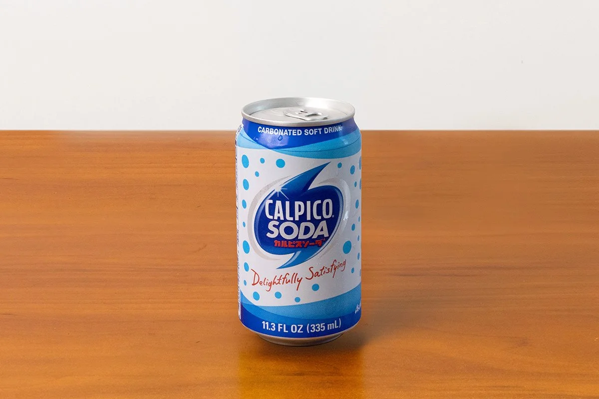 A can of Calpico Soda with blue and white packaging on a wooden surface.