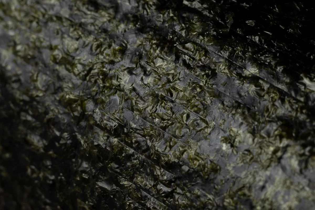 Close-up of a sheet of roasted seaweed with a dark, crinkled, and glossy texture.